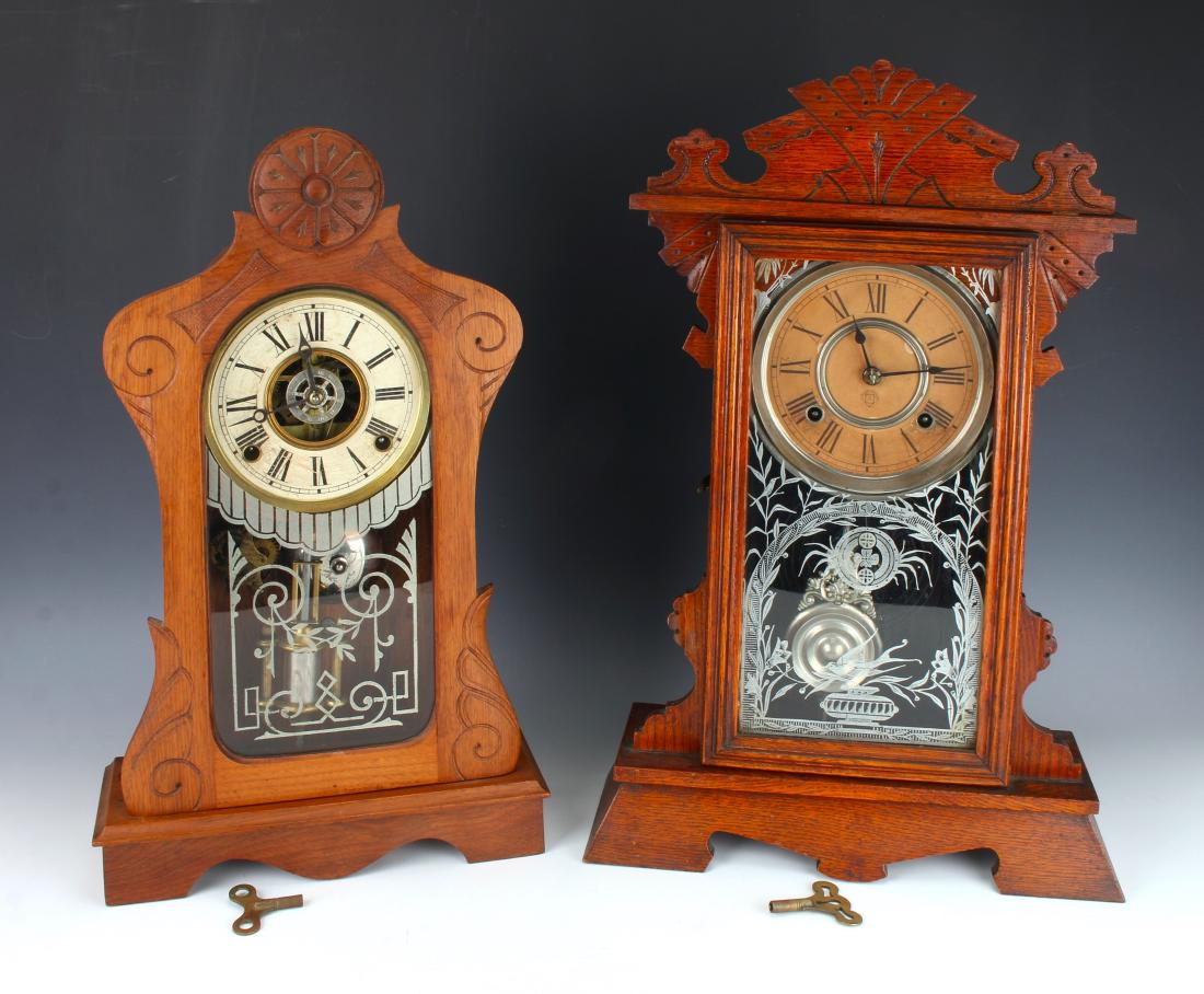 TWO MANTEL CLOCKS ANSONIA & GILBERT: TWO MANTEL CLOCKS ANSONIA & GILBERT: The both have reverse stenciled silver designs on the front glasses. Both are in shaped oak cases with incised eastlake patterns. The Asonia is marked on the d