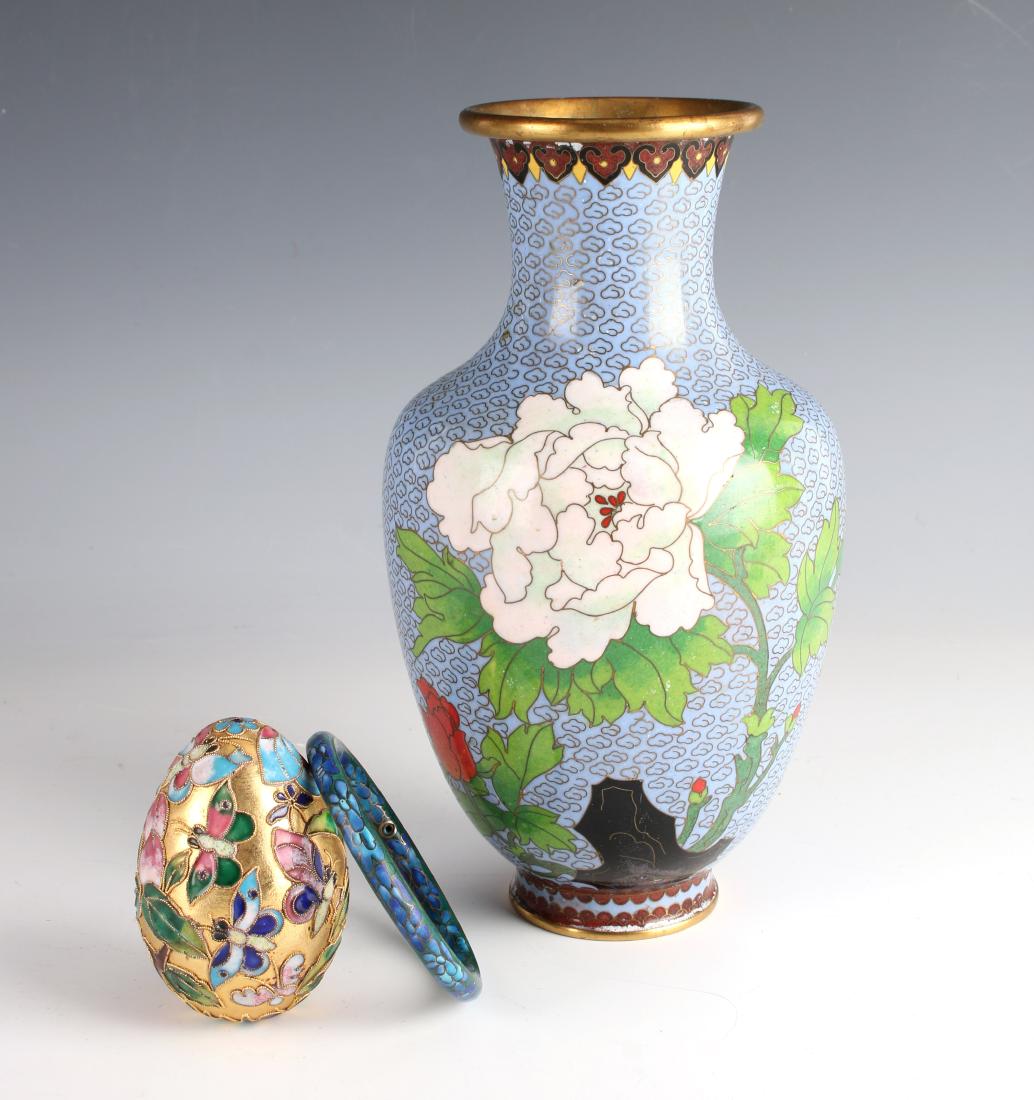 ASSEMBLED LOT OF CLOISONNE: ASSEMBLED LOT OF CLOISONNE: A vase, a decorative egg, and a bracelet. The vase has a pale blue background with cloud patterns and bright flowers. The egg has a garden scene filled with butterflies and
