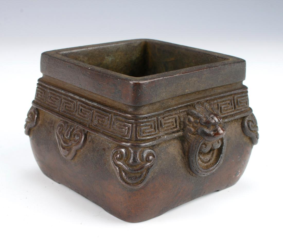 ANTIQUE CHINESE BRONZE CENSER: ANTIQUE CHINESE BRONZE CENSER: With a square rim and a rounded body. Has lion head handles with attached rings. A meander border over a ruyi border. Marked on the bottom. 3 1