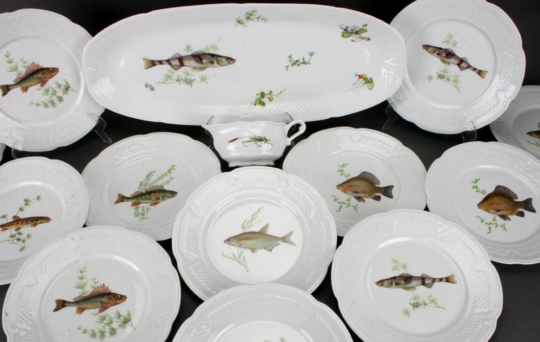 LOUIS LOURIOUX PORCELAIN FISH SERVING SET: LOUIS LOURIOUX PORCELAIN FISH SERVING SET: Large oval fish platter with white on white net border, sauce boat, and twelve dinner plates. The dinner plates all have a central image of a different fish