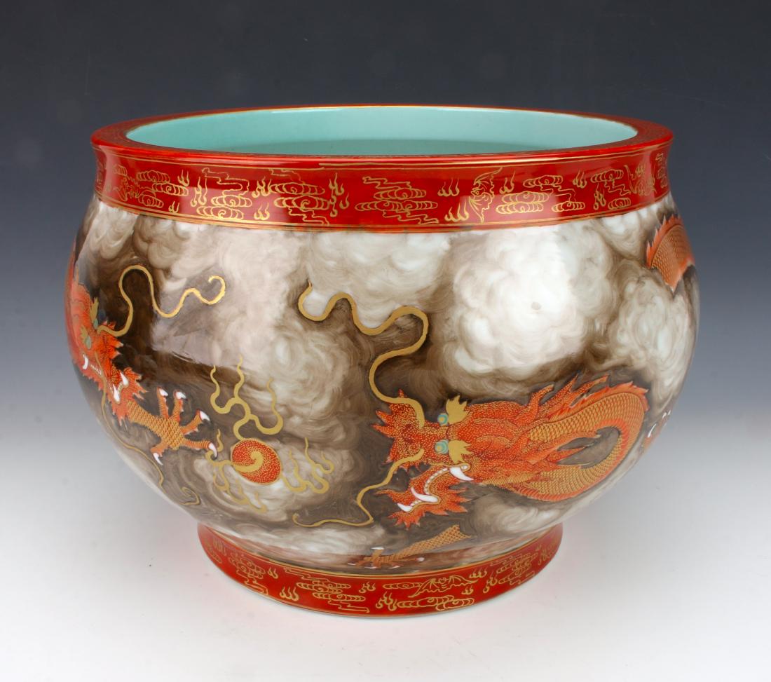 LARGE PORCELAIN DRAGON PLANTER: LARGE PORCELAIN DRAGON PLANTER: Two orange dragons face each other in a smoky cloud-filled sky, each reaching for a flaming pearl. Swirls of brown imitate smoke that the dragons weave in and out of, w