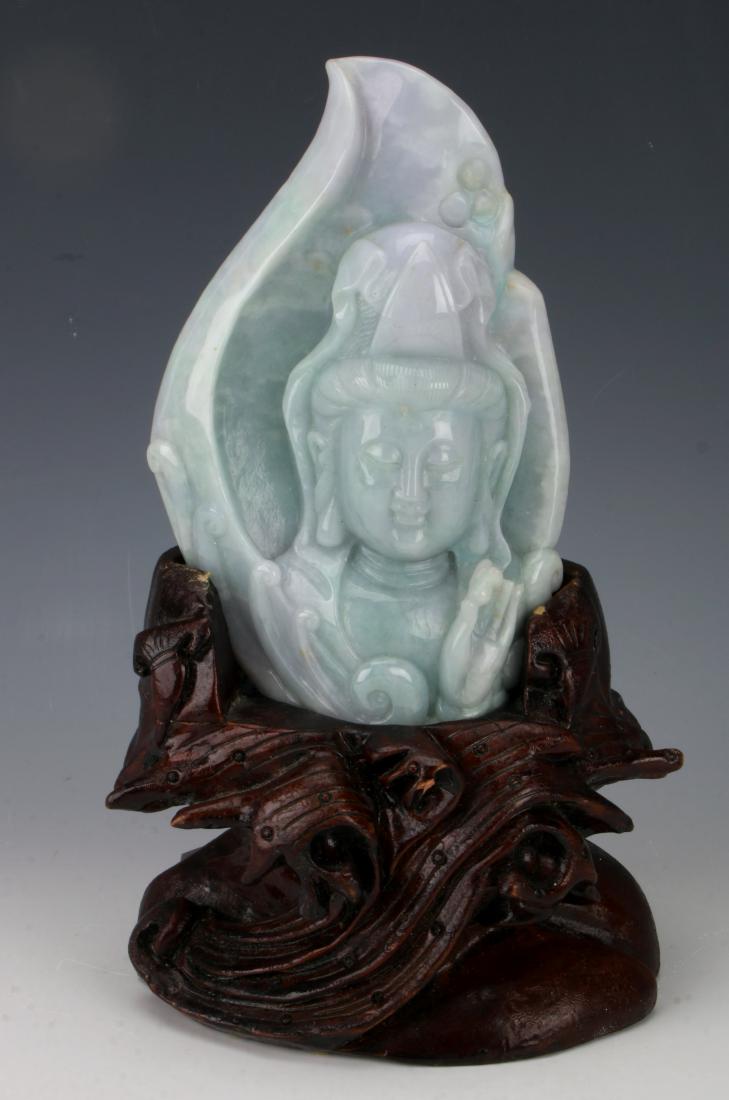 CARVED JADE BUDDHA IN CUSTOM STAND: CARVED JADE BUDDHA IN CUSTOM STAND: Carving of the head of Buddha showing one hand holding a pearl, and a leaf form behind his head. Fits in a custom stand representing waves.