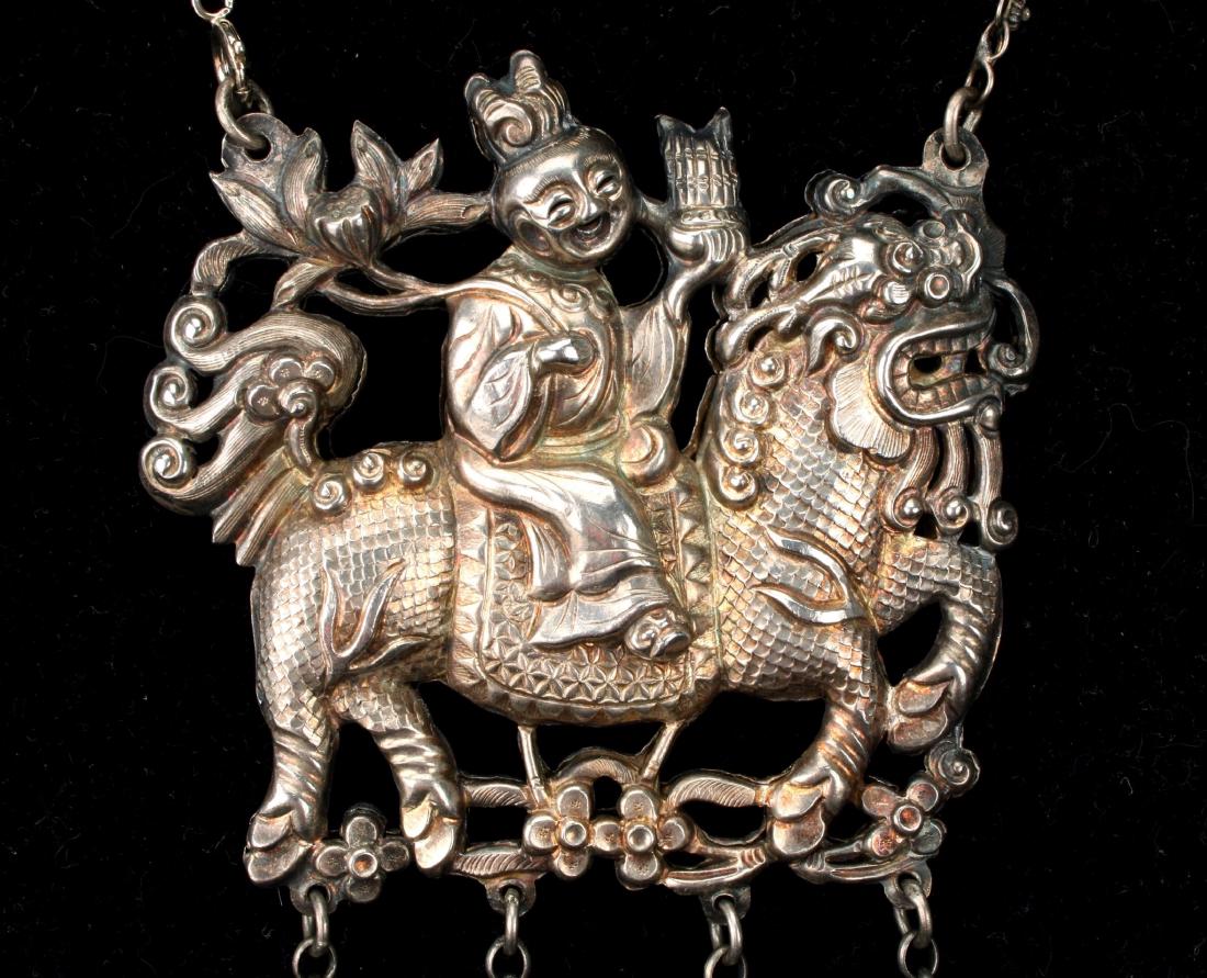 CHINESE REPOUSSE LION NECKLACE: CHINESE REPOUSSE LION NECKLACE : A rider is atop a lion, four bell forms on chains hang from the lion's paws. Figured on both sides. Chains: 17" Pendant: 3"<