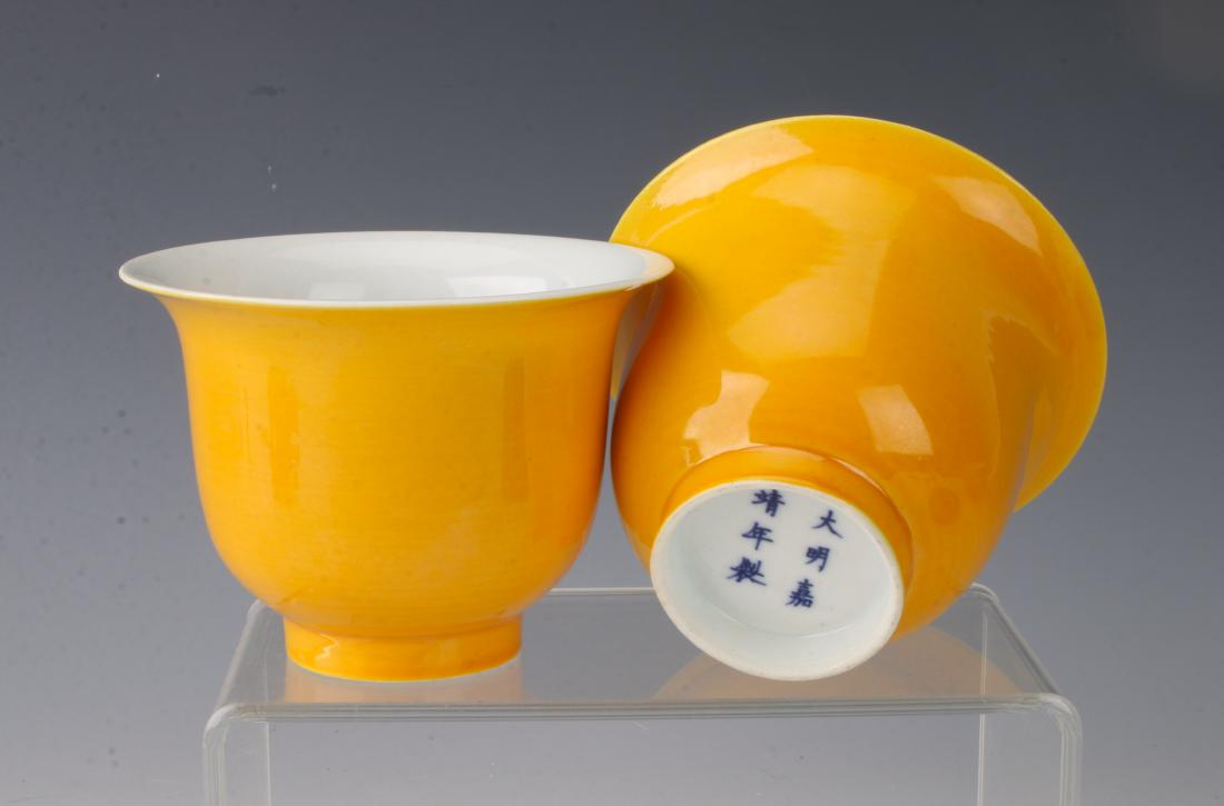 PAIR OF YELLOW CUPS: PAIR OF YELLOW CUPS: Two buttercup yellow glazed tea cups on a lot foot. White glaze on the interior. Marked on the bottom. 4" X 2 3/4" $100 - $200