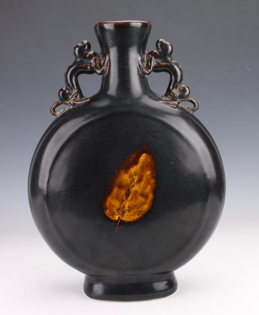 CHINESE JIZHOU WARE BLACK GLAZE WITH LEAF VASE: CHINESE JIZHOU WARE BLACK GLAZE WITH LEAF VASE: Pierced applied dragon handles, and a leaf on each side. 10" X 14 1/2" $200 - $400