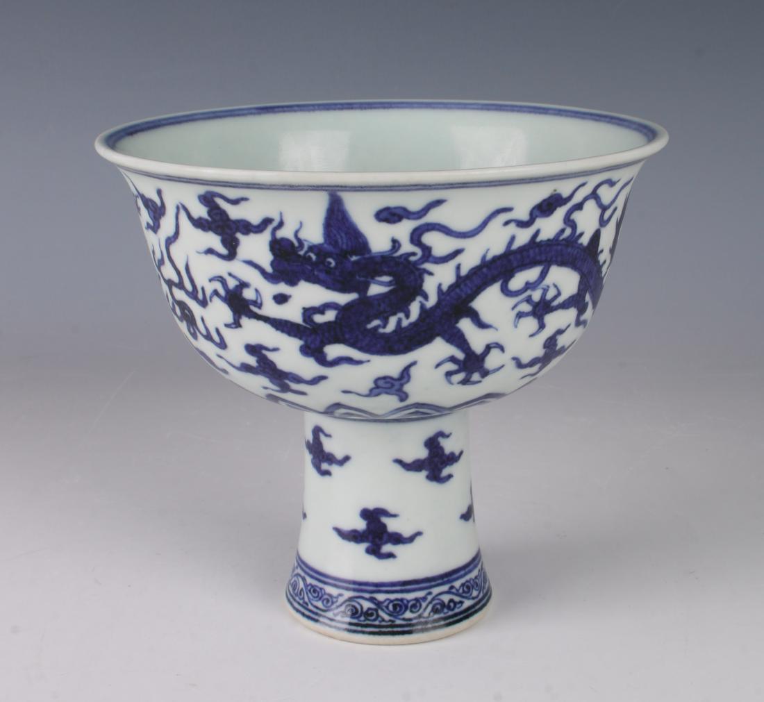 BLUE & WHITE HIGH HEELED DRAGON CUP: BLUE & WHITE HIGH HEELED DRAGON CUP: Two dragons chase each other around the exterior of the cup, clouds swirl around the stem of the cup. The bottom is bordered with a tendril design. The interio
