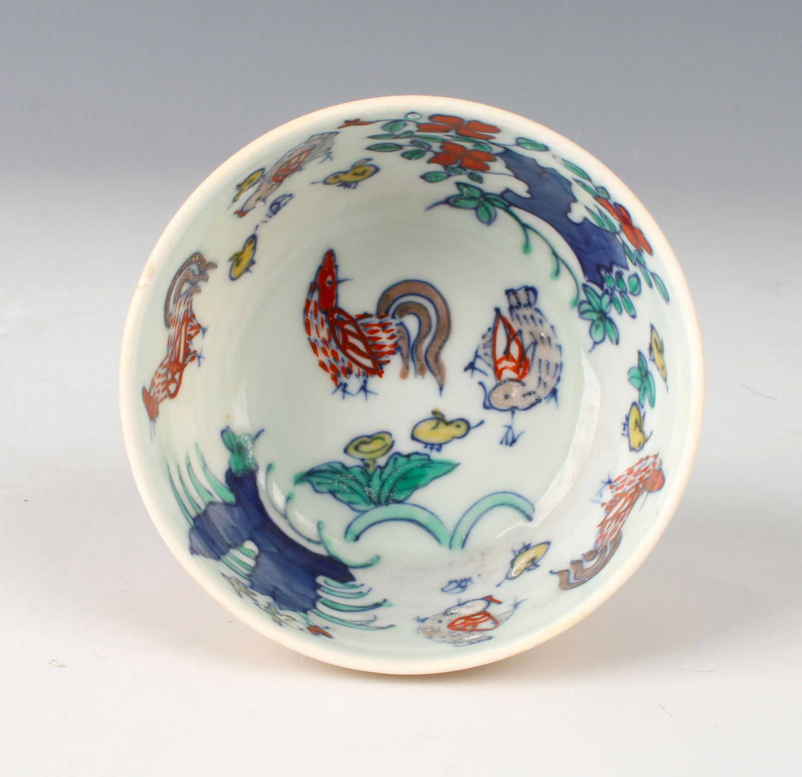 WUCAI ROOSTER THIN PORCELAIN TEA CUP: WUCAI ROOSTER THIN PORCELAIN TEA CUP : A rooster, hen, and chicks are on the inside of the cup with flowers and boulders. Glazed in yellow ochre on the outside. When put to light you can see some of t
