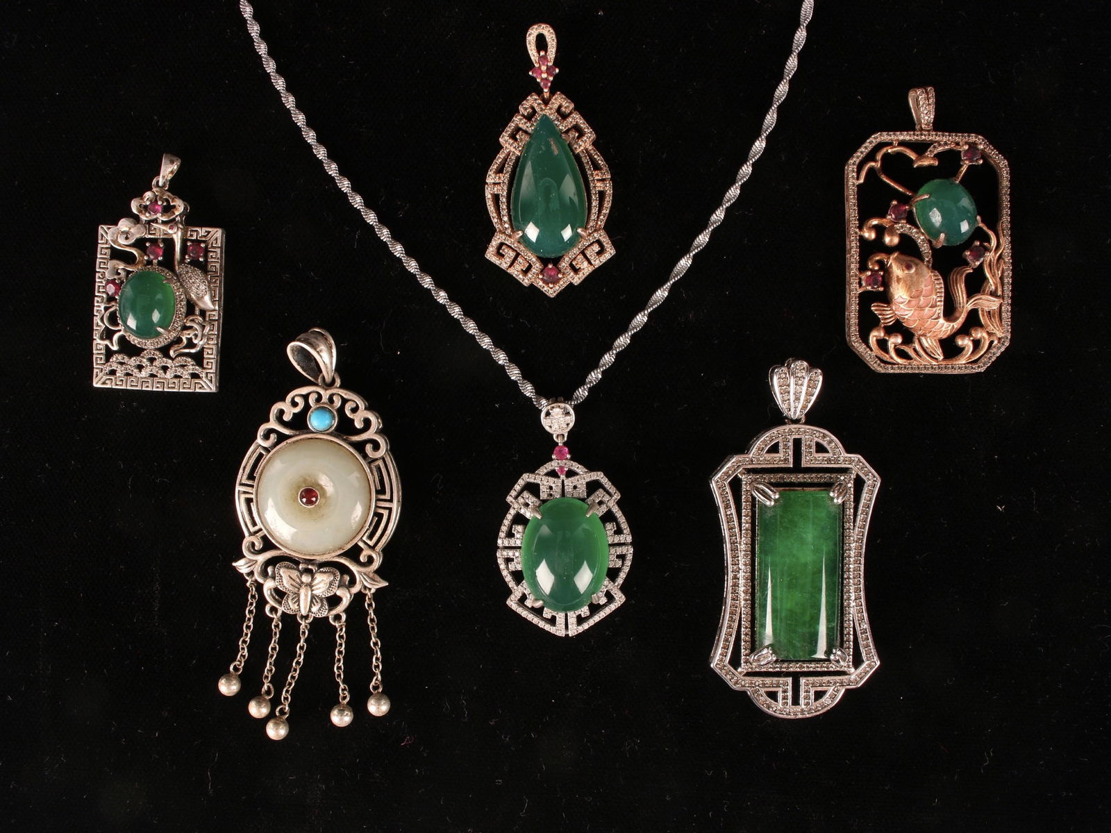 LOT OF 7 JADE & SILVER PENDANTS: LOT OF 7 JADE & SILVER PENDANTS: In various settings. White and green jade cabochon stones. One has a chain that is marked. One is Tibetan style with bi disc and garnet. One is a fish. Three have