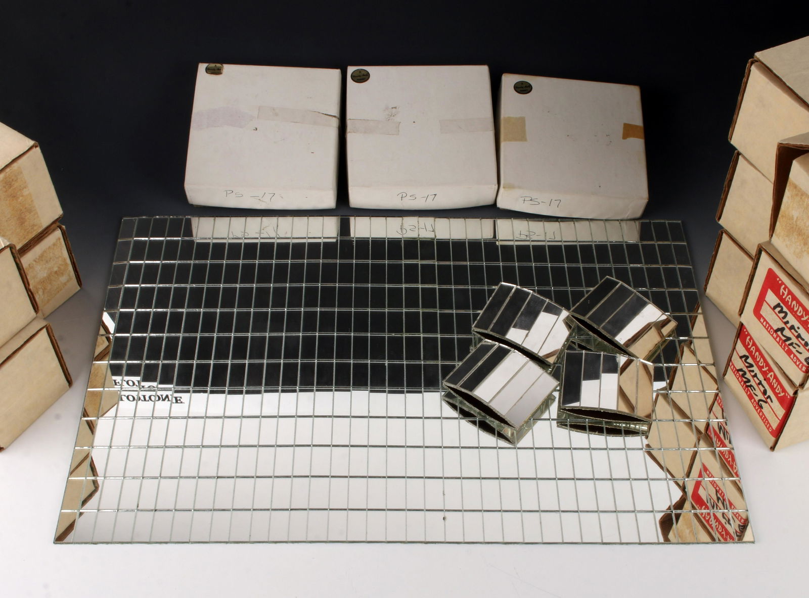 8 PLACEMATS & 12 NAPKIN RINGS MIRROR TILE: 8 PLACEMATS & 12 NAPKIN RINGS MIRROR TILE: Comprised of mirrored tiles glued to a fabric background. In original boxes. Three packages of napkin rings, four in each. Old stock, new in box. Labeled