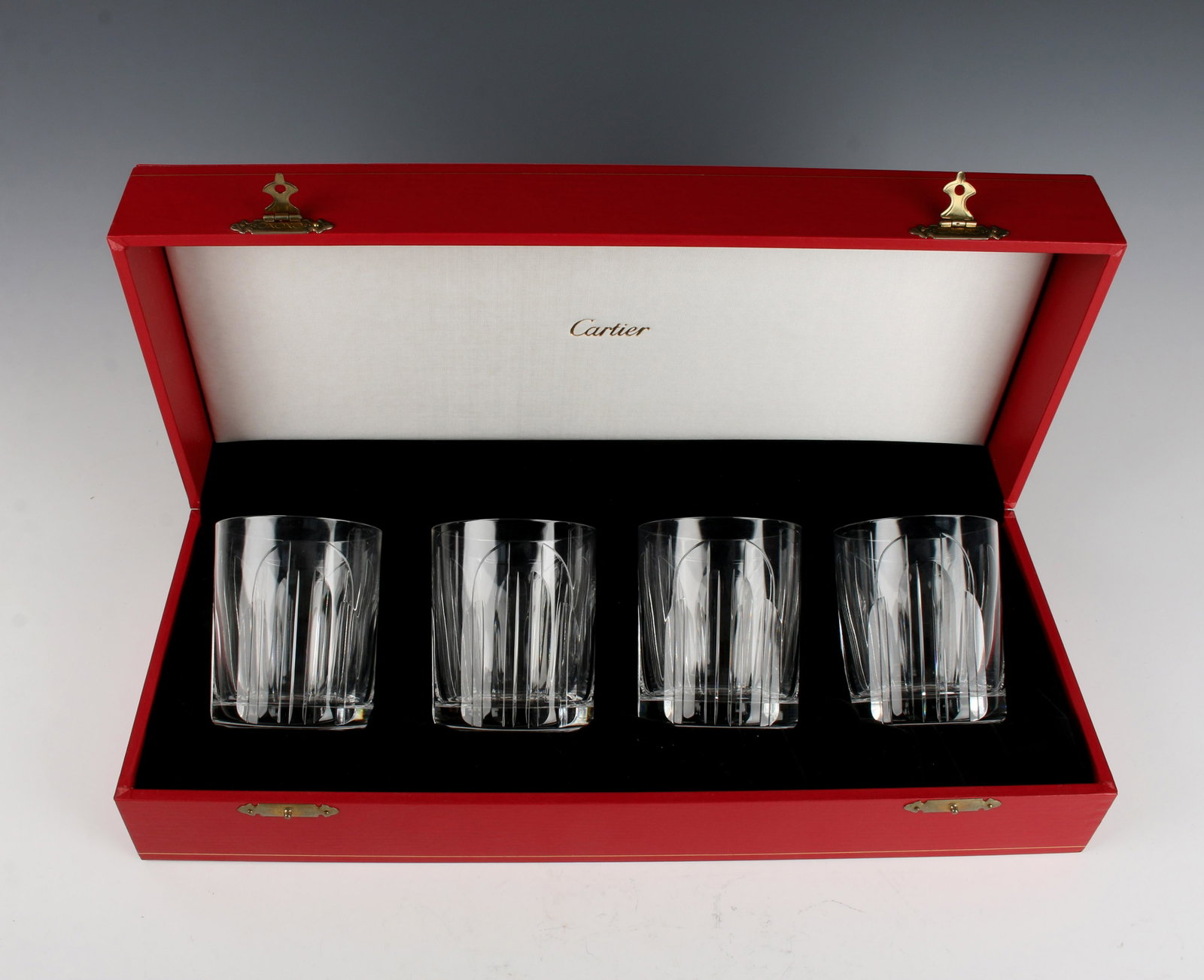 CARTIER CRYSTAL TUMBLERS IN PRESENTATION BOX: CARTIER CRYSTAL TUMBLERS IN PRESENTATION BOX: Four Cartier etched crystal rocks glasses. New in box in red and gold presentation box, never