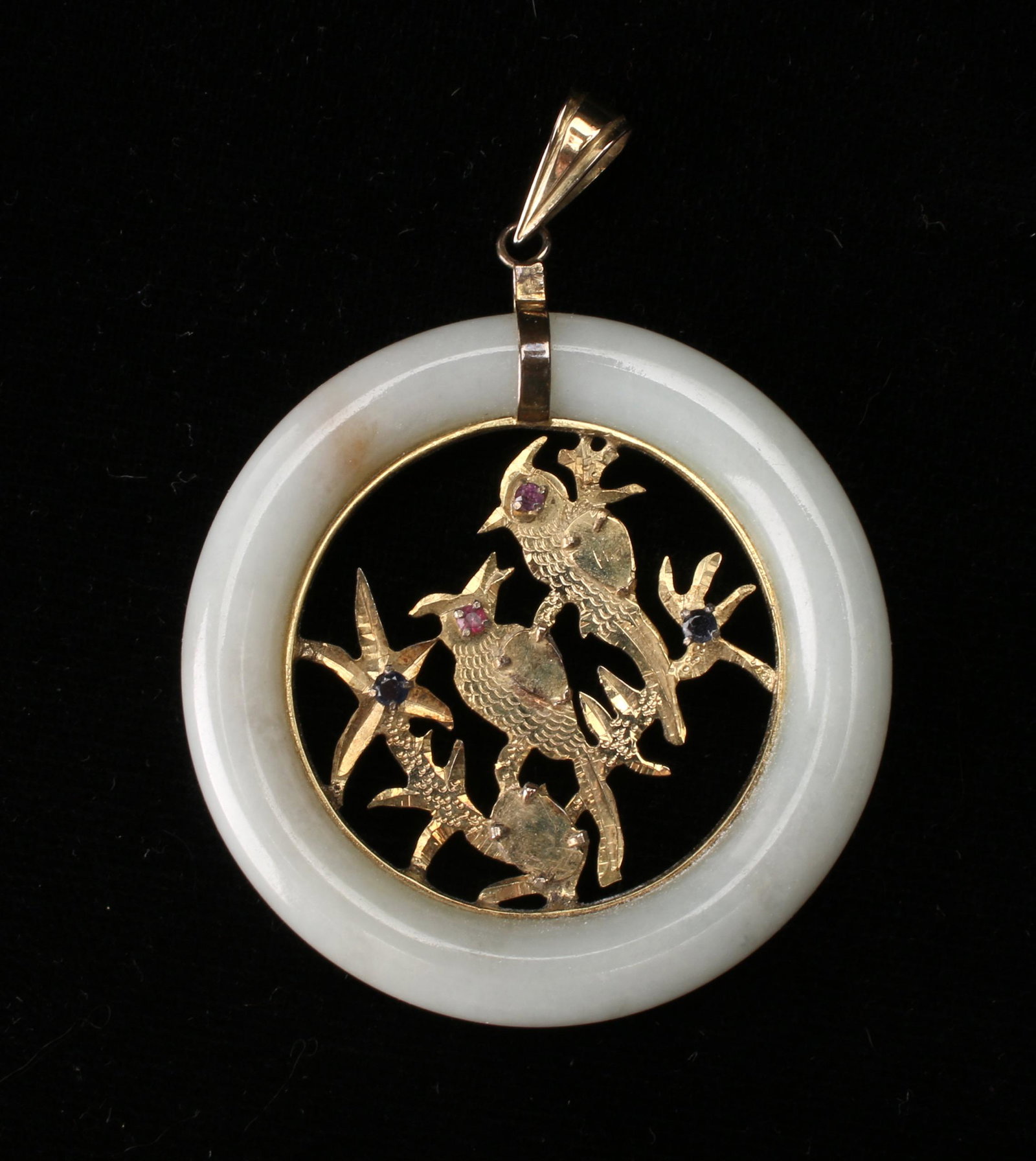WHITE JADE 14K YELLOW GOLD PENDANT: WHITE JADE 14K YELLOW GOLD PENDANT: White jade ring around a pair of lovebirds in a tree. The birds have ruby eyes, there are sapphires as flower centers. Could be worn on either side. Bale marked 14k