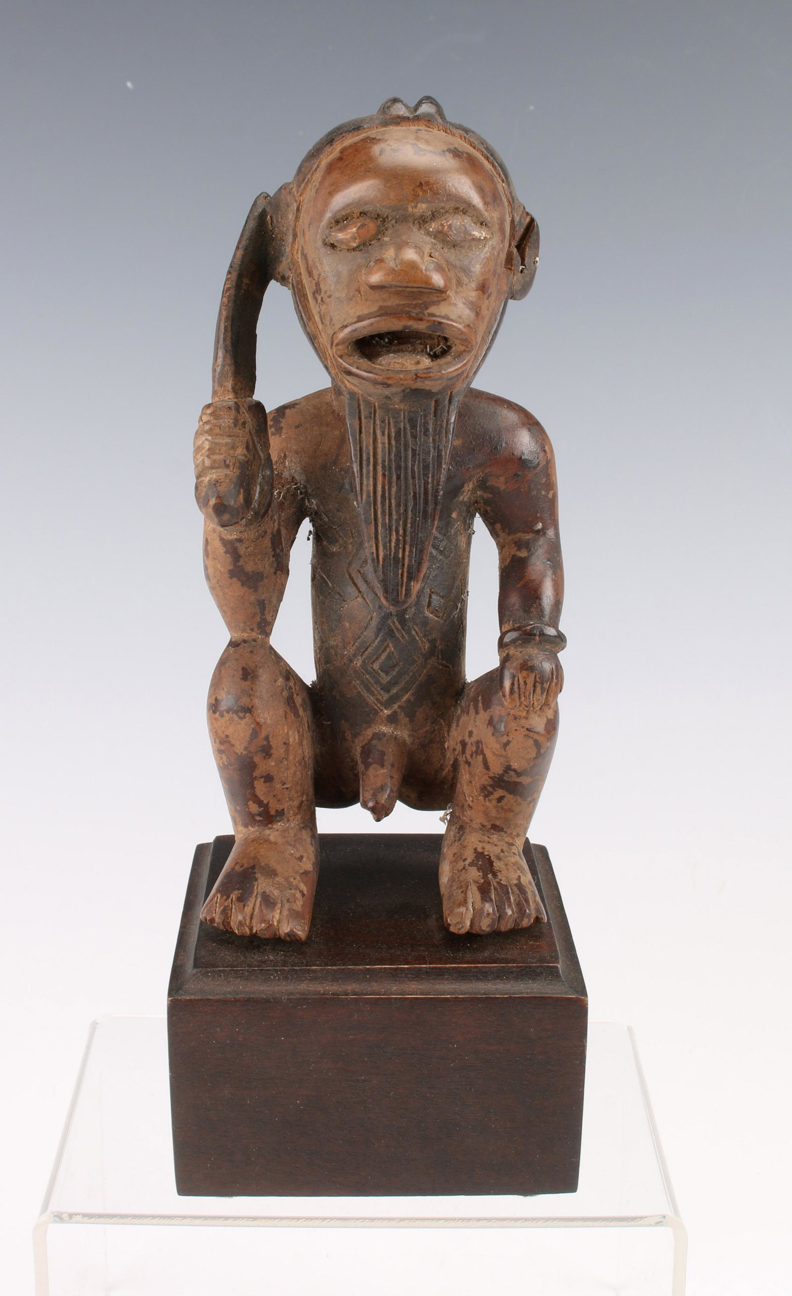 CARVED AFRICAN BEMBE FIGURE: CARVED AFRICAN BEMBE FIGURE: Crouching male figure holds a knife in one hand. He has a long beard and open mouth. Incised body representing tattoos. 3" X 8"<