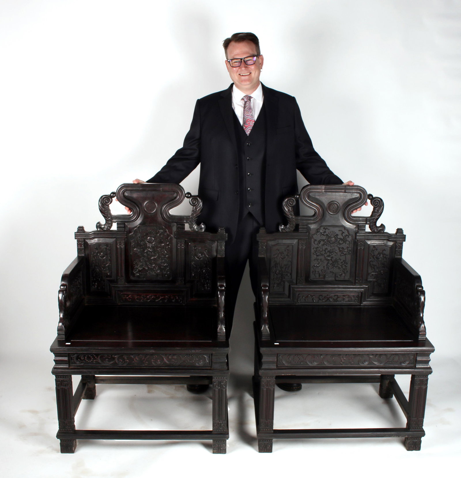 PAIR OF CARVED ZITAN THRONE CHAIRS: PAIR OF CARVED ZITAN THRONE CHAIRS: The backsplat is carved in panels of flowers and tendrils, the top has a medallion with a central character. Feather-like columns flank the top and are at the end o