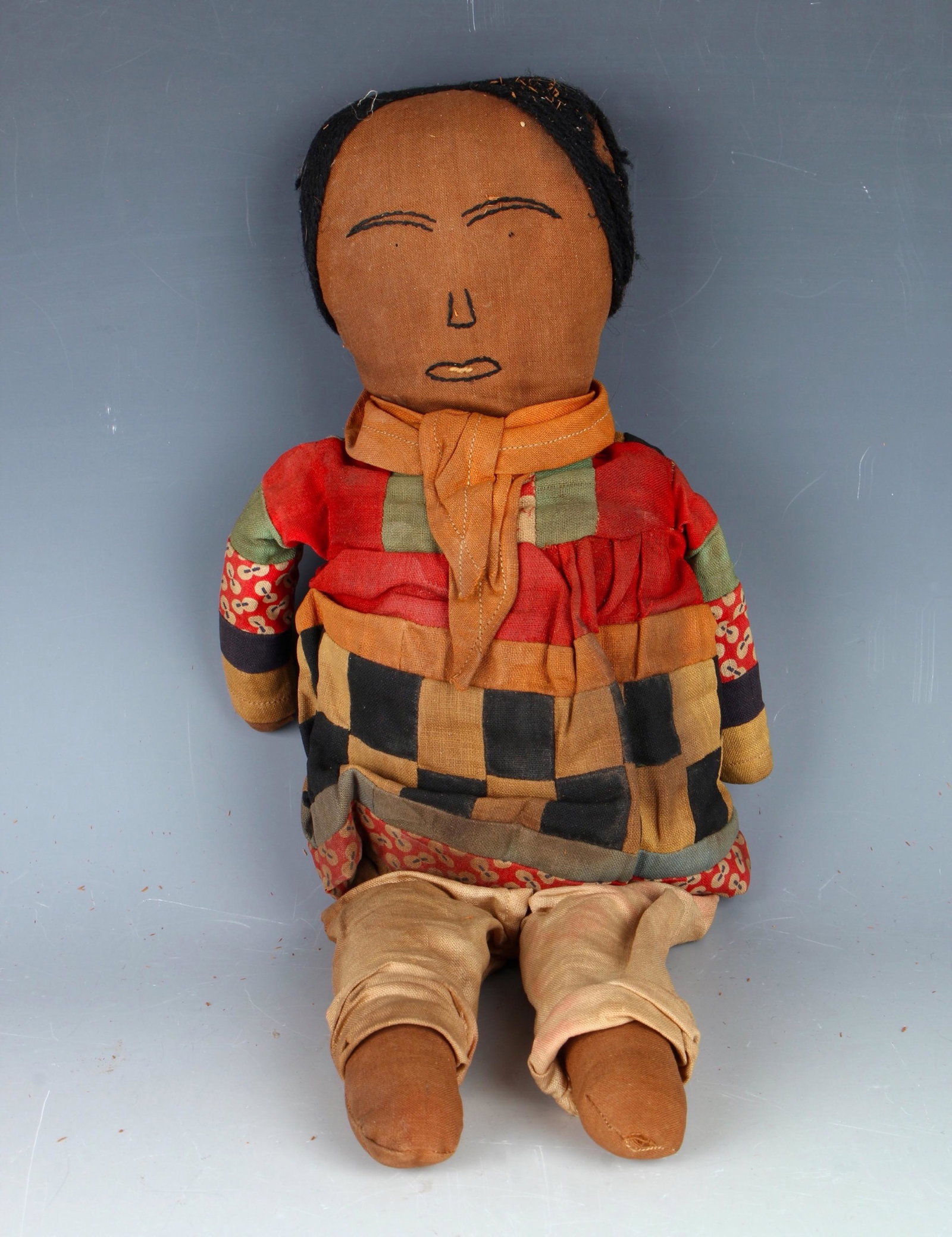 ANTIQUE BLACK AMERICANA FOLK RAG DOLL: Cloth man stuffed with sawdust wearing a patchwork shirt and neck scarf. Yarn hair and embroidered facial features. 14" $40 - $80 Please contact us for high resolution images of this lot.