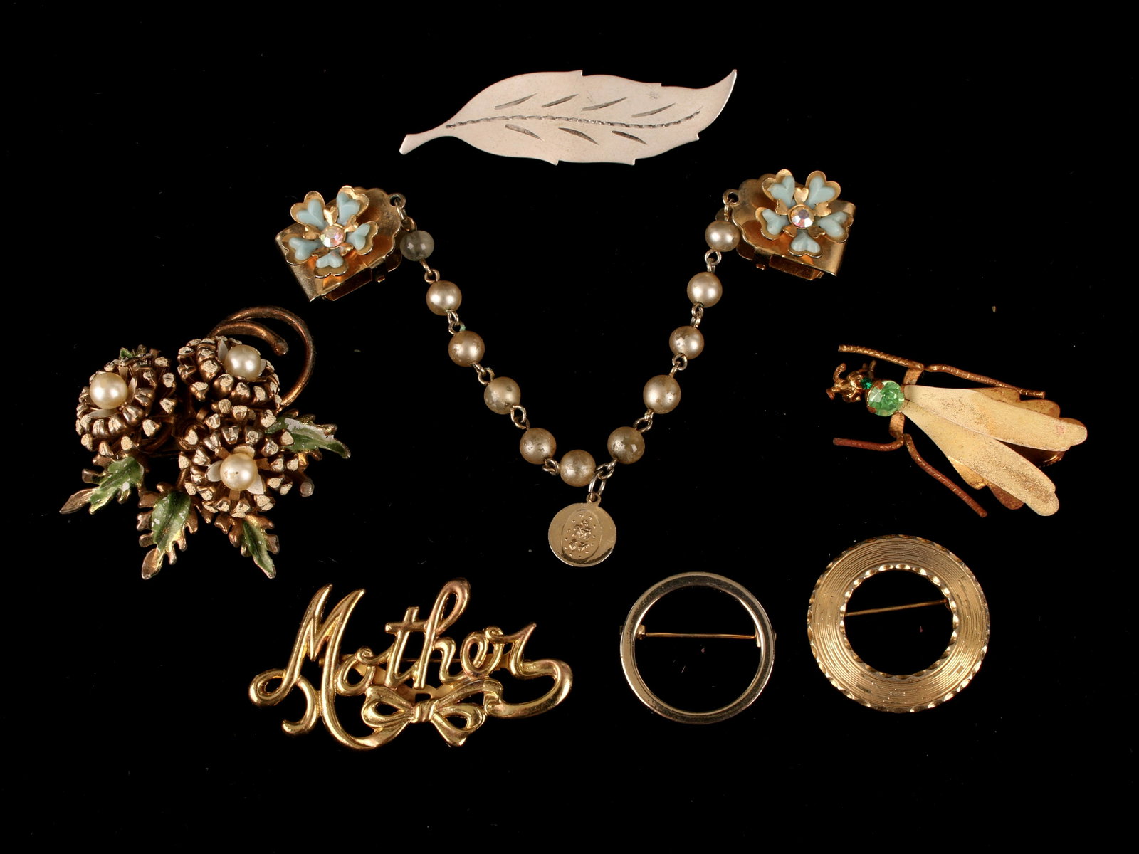 ASSEMBLED LOT OF COSTUME JEWELRY PINS BROOCHES: Sweater clip, two circle pins, a bug, a leaf, 'mother', and a floral pin. $100 - $200 Please contact us for high resolution images of this lot. Shipping: We are able to pack and ship this i