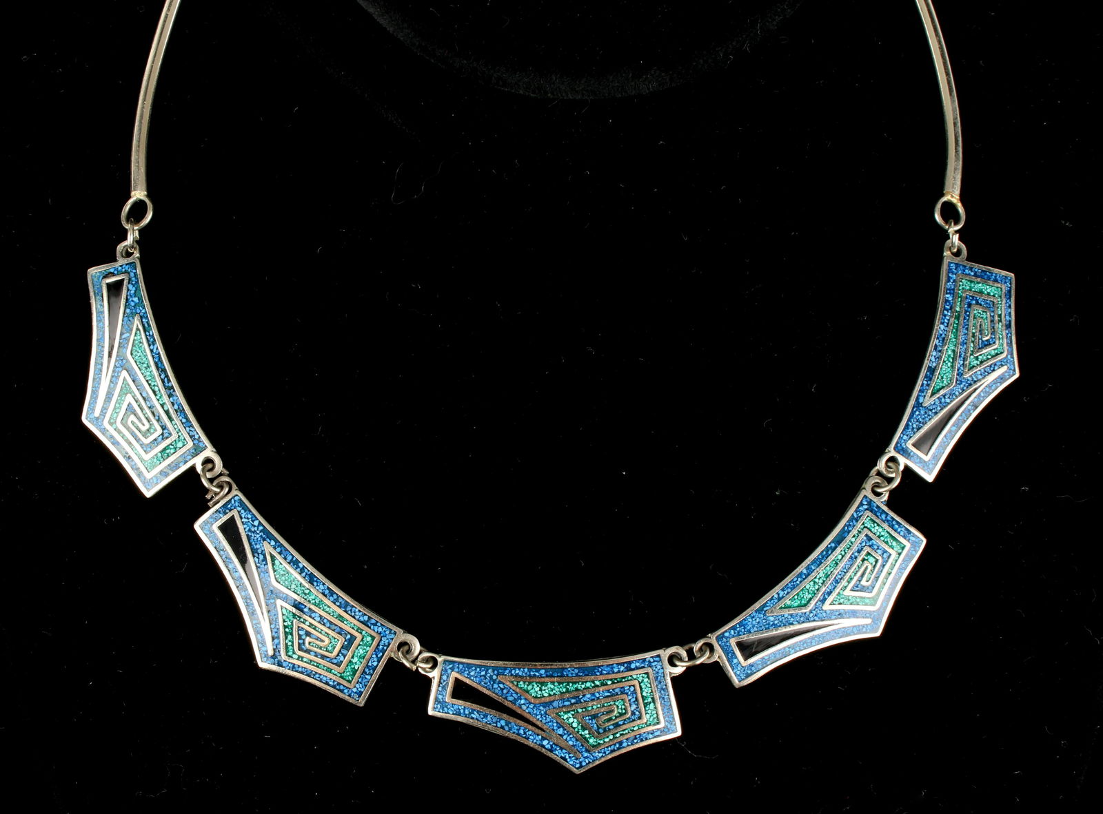 STERLING INLAID ALPACA MEXICAN TURQUOISE NECKLACE: Five geometric inlaid segments are joined by four segmented bars. The inlaid segments have crushed turquoise and malachite, and onyx triangles. Designed to lay smoothly at the base of the neck. Weight