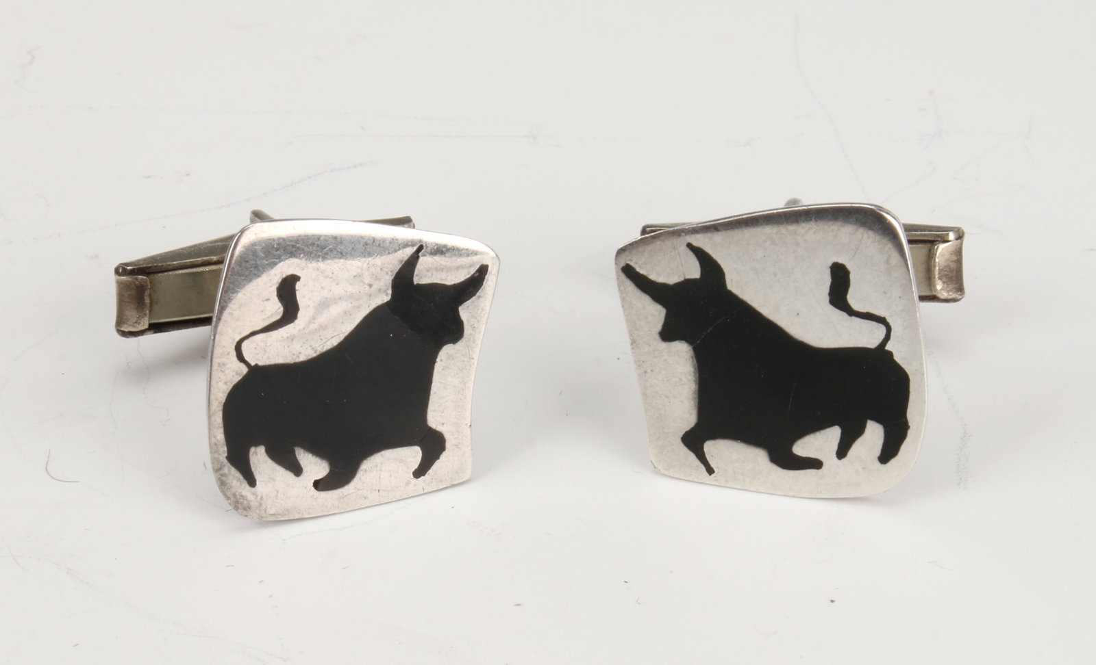TAXCO STERLING BULL CUFFLINKS: Black inlaid onyx silhouettes of bulls prance on bright silver backgrounds. Stamped 925 Taxco sterling. Consigned by Philadelphia collector of 1940s Mexican and Native American sterli