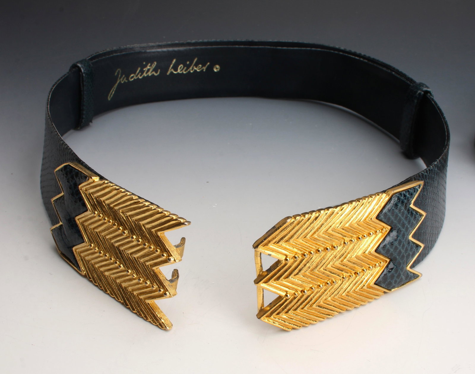 JUDITH LIEBER DARK TEAL GOLD SNAKE BELT BRIGHTON: Shaped Judith Lieber adjustable snake patterned leather belt in a dark teal blue with textured gold buckle. Brighton two tone and alligator patterned leather belt size M. 37" x 2" $100 - $