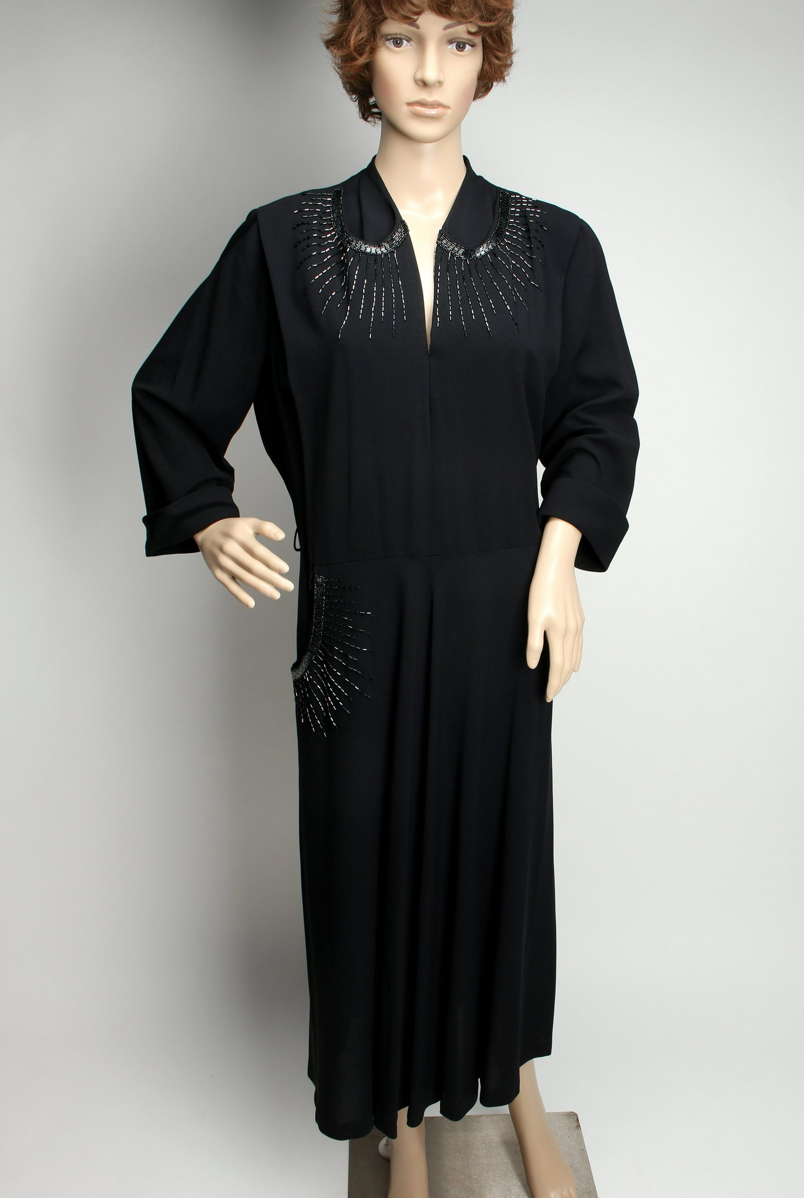 VINTAGE 1940S BLACK BEADED EVENING DRESS: Classic 1940s jet bead embellished cocktail dress. Sunburst lines radiate from curved collar area. Mirrored on a single right hand pocket. 3/4 cuffed sleeves. Shoulder seam: 16 1/2". Waist: 19 3/