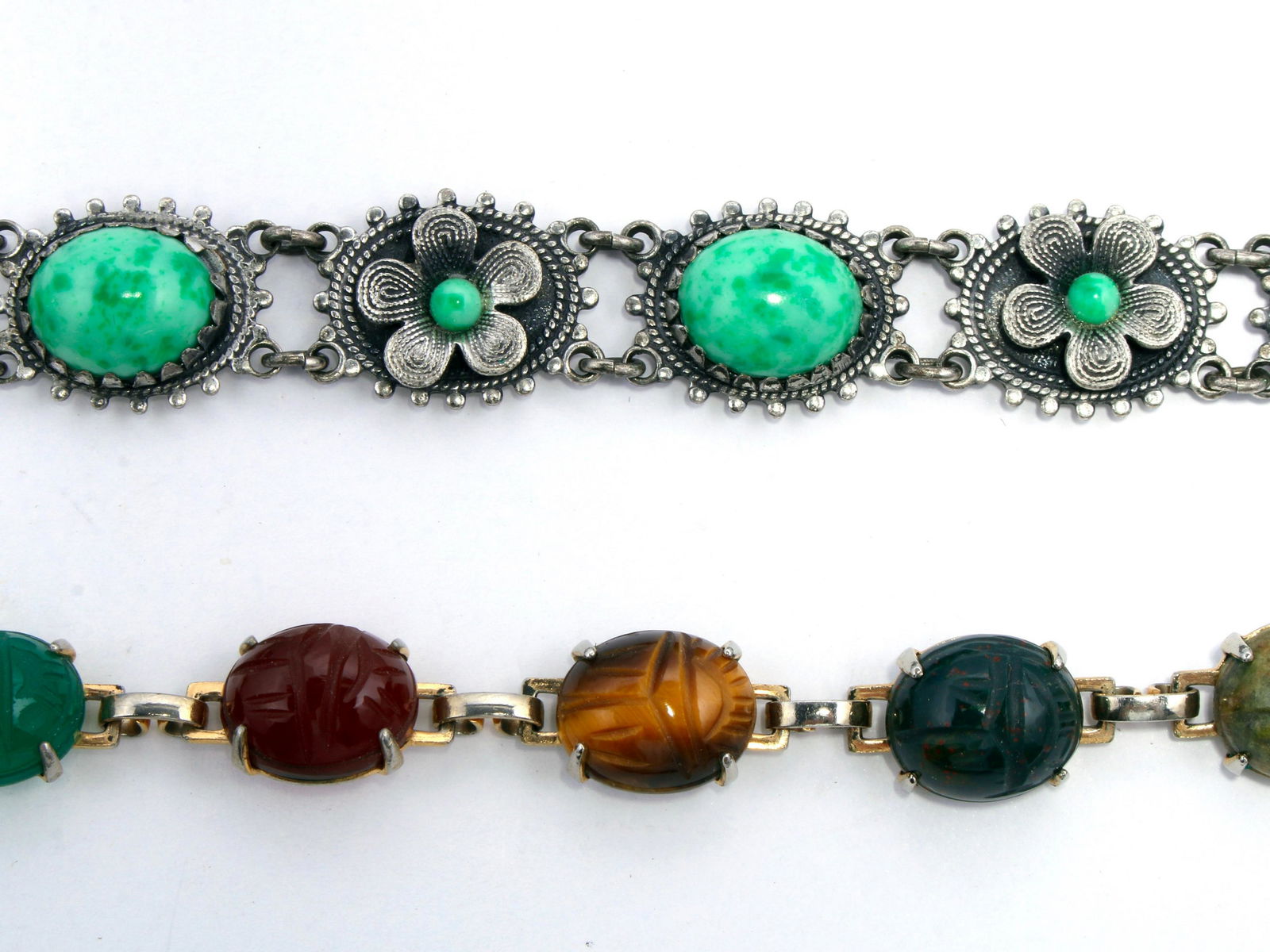 VINTAGE SEMIPRECIOUS STONE LINK BRACELETS: One is multicolor scarabs including tiger eye and jasper with a safety clasp. The other is a silver tone alternating flower and oval cabochon green stones. Has an unusual snap clasp. 7 1/4" $4