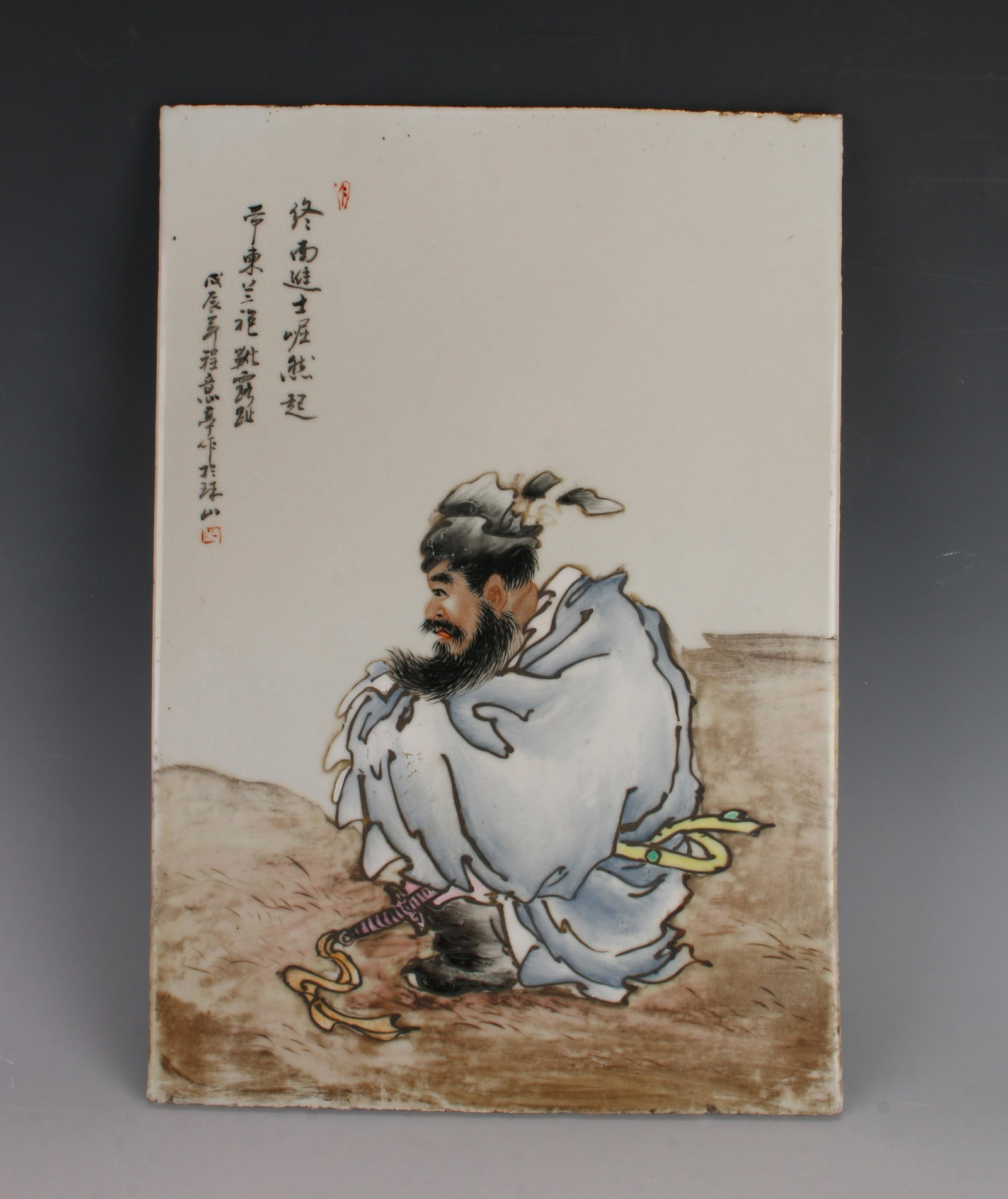 CHINESE PORCELAIN PLAQUE OF SEATED MAN: Dramatic portrayal of a seated man. You can see the hilt of his sword peeking from his robes. He has a full beard. Calligraphy and artist marks on upper left. 10" X 14 1/4" $200 - $400