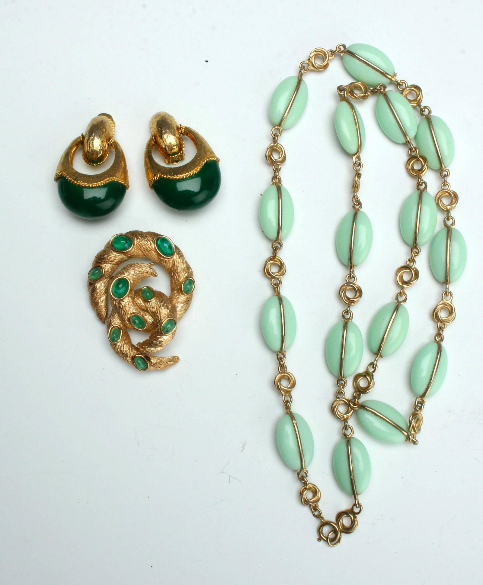 VINTAGE COSTUME JEWELRY LOT TRIFARI: Vintage Trifari pin with hanging element that has textured gold with cabochon green stones. Gold door knocker earrings with large green lower elements. And pale glass and love knot necklace. $40 - $8