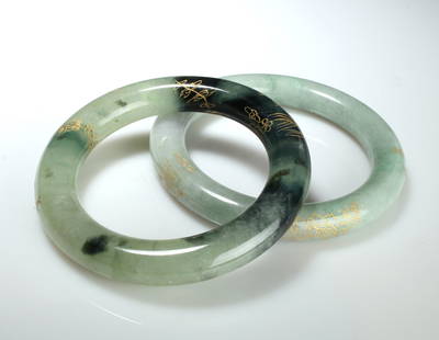 TWO JADE BANGLES: The paler bracelet is incised with characters and other shapes. The other one has underwater plants including a lotus, telescope goldfish, plants, and characters. 3" $40 - $80 Please contact