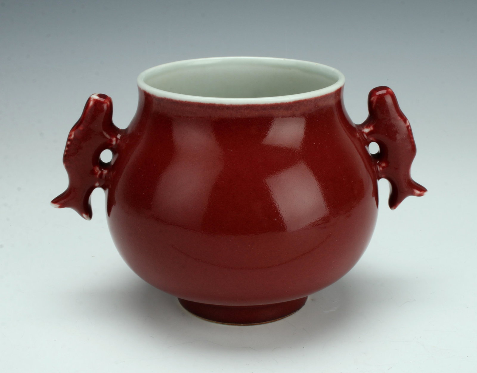 OX BLOOD HANDLED CENSER: Glazed on the outside on ox blood and flanked by handles shaped as fish. Interior is glazed white. Marked on bottom. 7" X 5" $200 - $400 Please contact us for high resolution images o