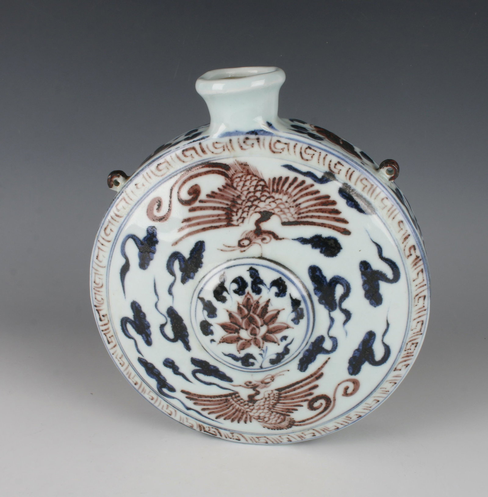 BLUE & RED PHOENIX MOON FLASK FORM: Two phoenixes face the circular lotus motif, blue clouds are on either side of them. A meander pattern borders the image. The side is decorated in flower and tendril. 10" X 2" $600 - $900