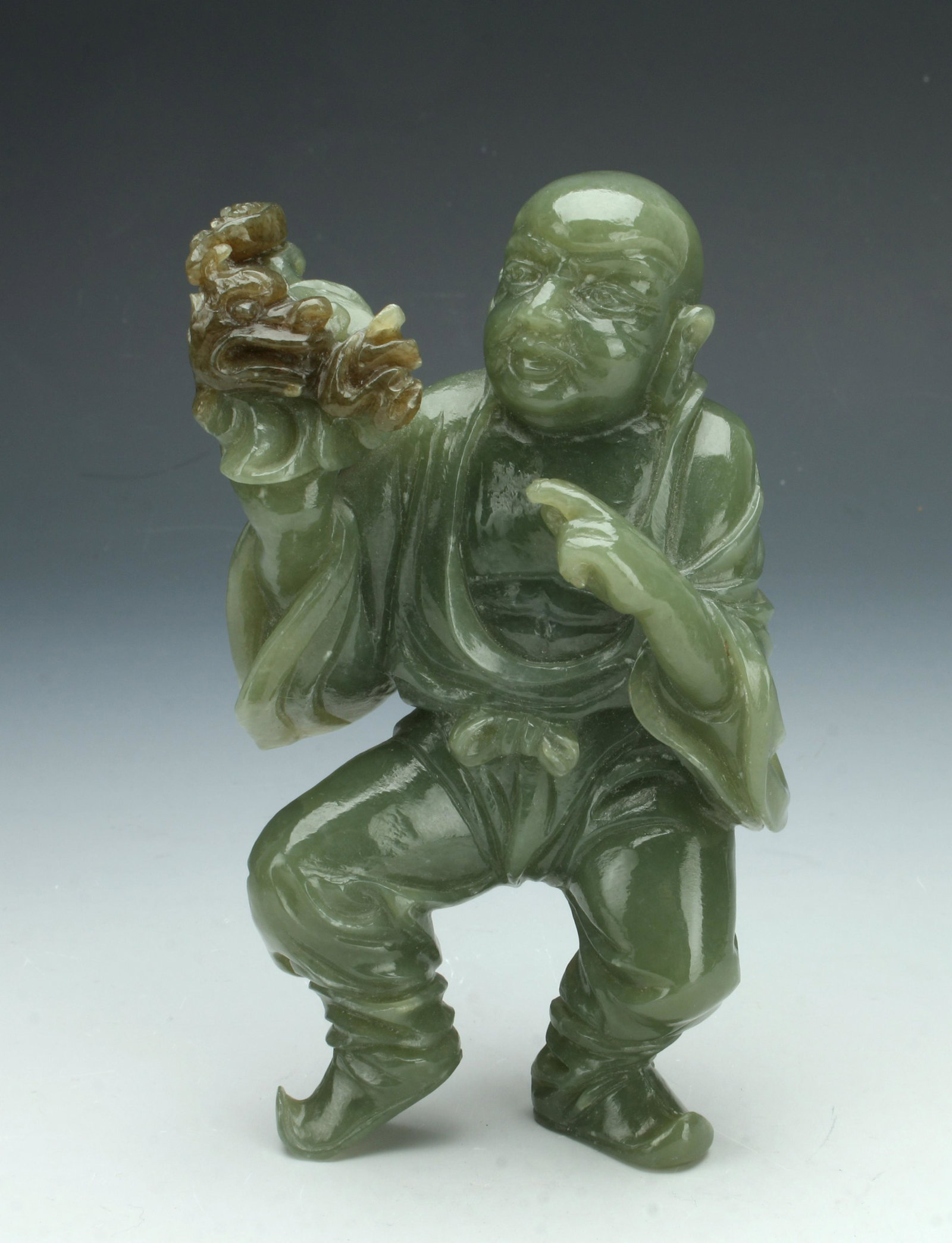 JADE BUDDHA WITH DRAGON: Standing jade Buddha holding a small dragon in one hand and pointing to it with the other hand. 5 1/2" $300 - $500 Please contact us for high resolution images of this lot. Shipping: