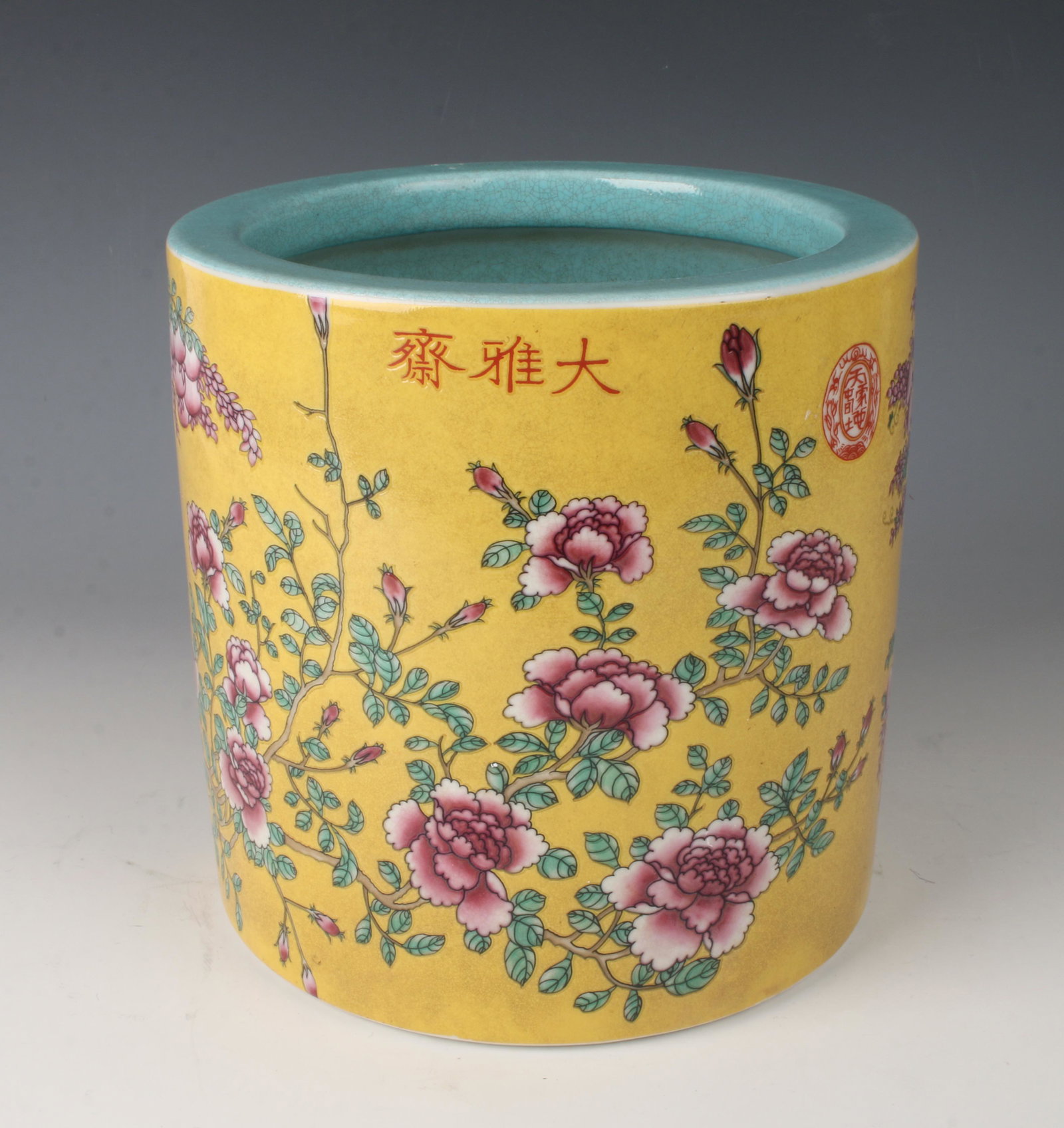 FAMILLE JAUNE BRUSH POT: Decorated with a bird in a garden of pink flowers and fruit on a yellow ground. Calligraphy in the top and an artist mark, below the rim. Marked on the bottom. 8" X 8" $500 - $800 Ple