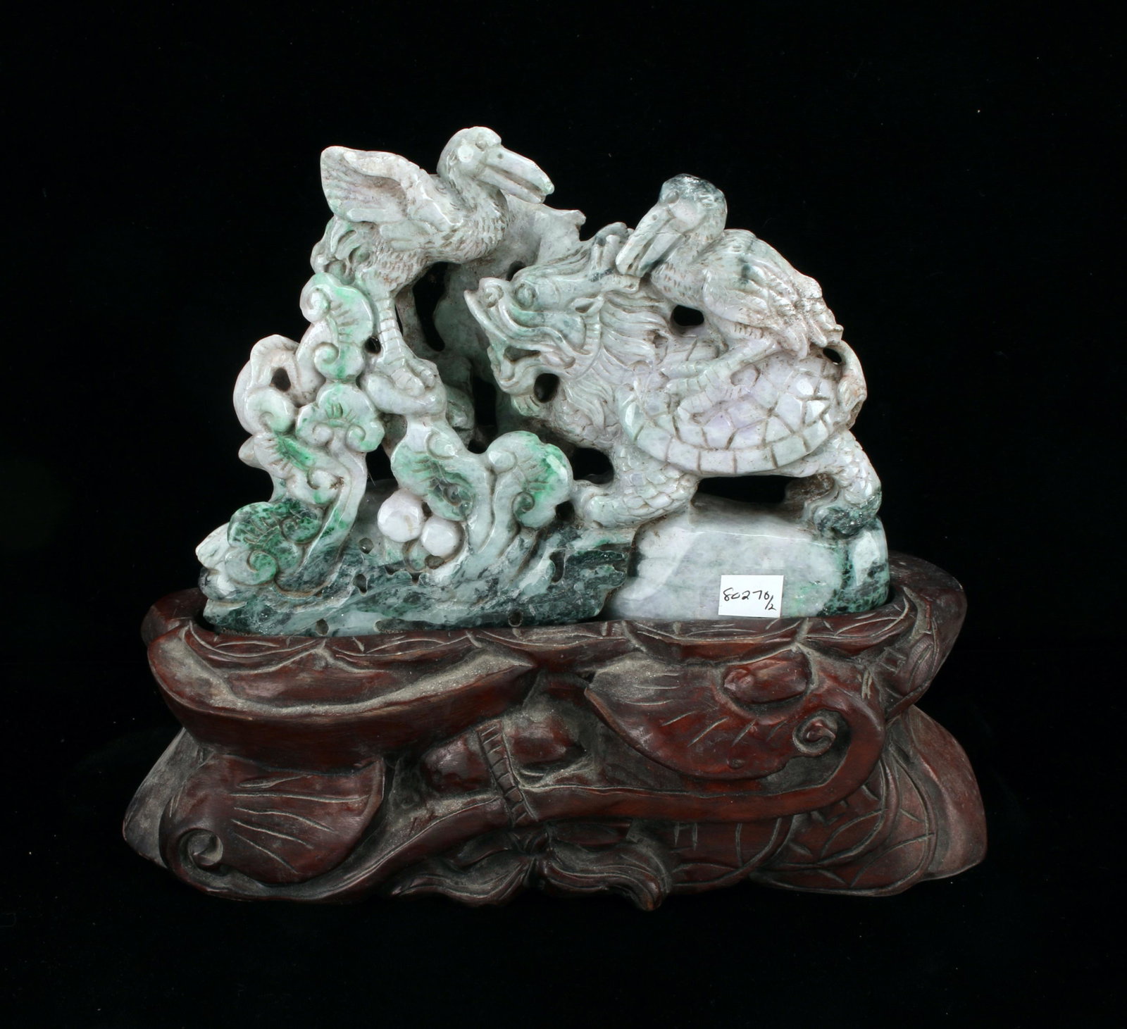 CARVED JADE OF MYTHOLOGICAL CREATURES ON STAND: Mythological creatures stand among a garden with a boulder and ruyi flowers. Has custom carved stand with ruyi flowers. 9 1/2" X 9" $300 - $500 Please contact us for high resolution i