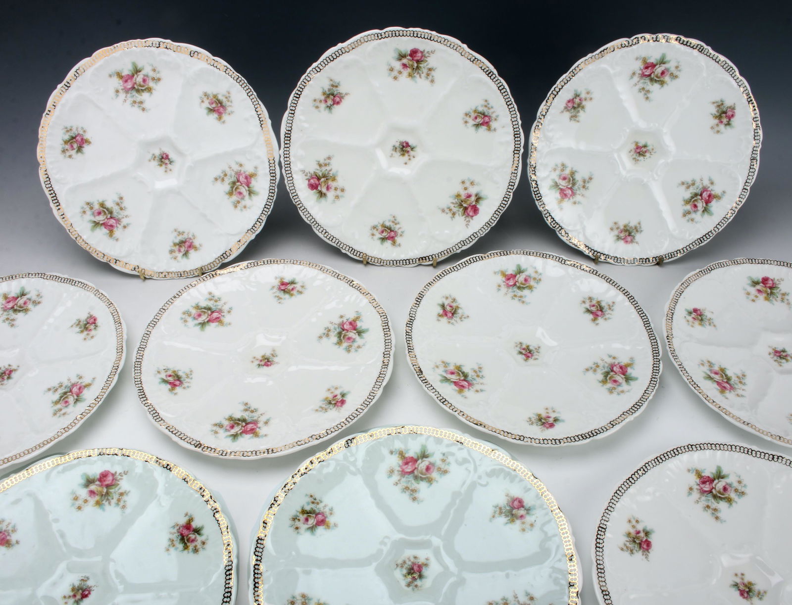 12 ANTIQUE O. & E. G. ROYAL AUSTRIA OYSTER PLATES: Hand painted in roses and flowers accented in gold. Set of a dozen. 9.5" x 7" $200 - $400 Please contact us for high resolution images of this lot. Shipping:
