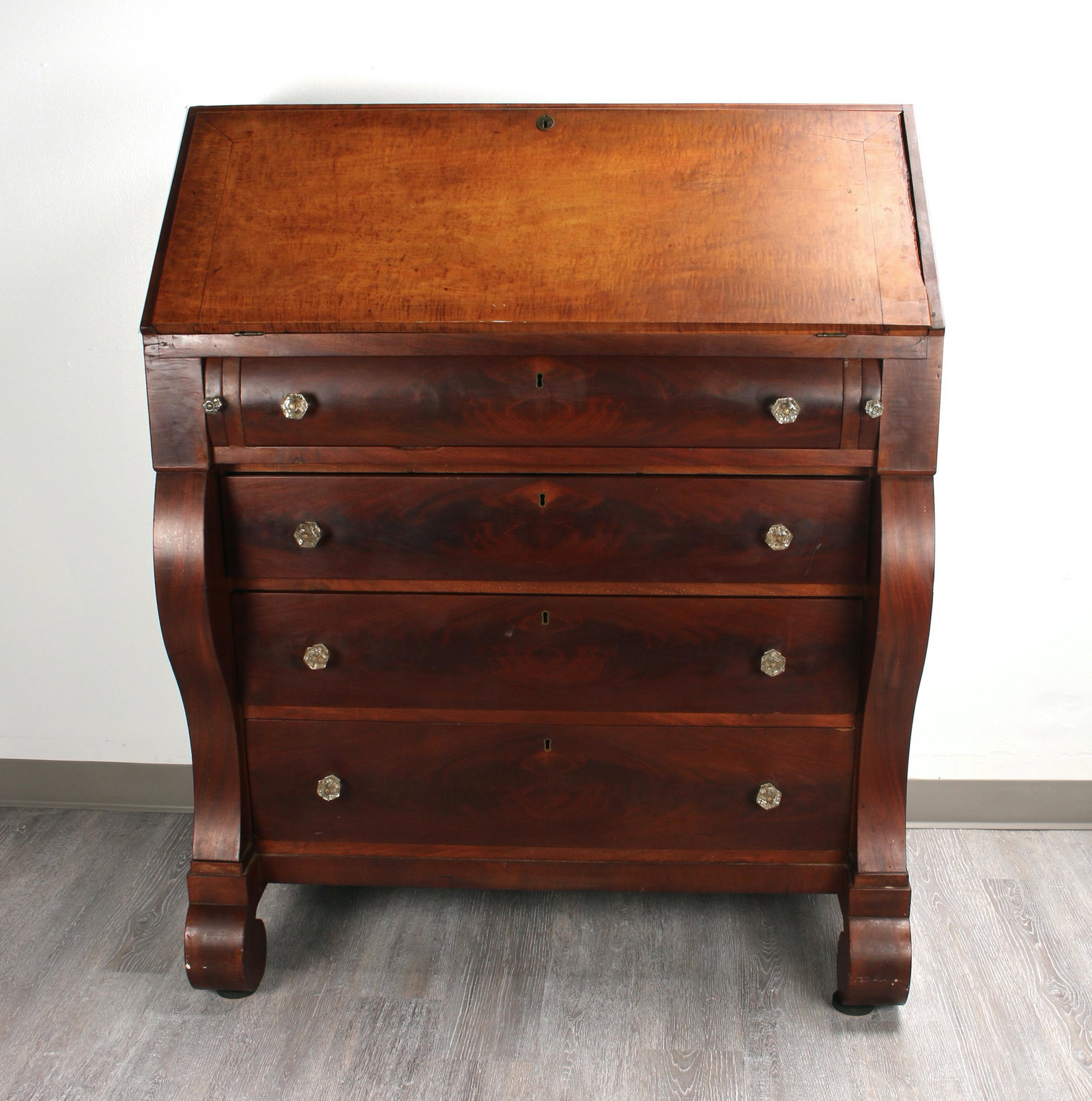 ANTIQUE AMERICAN EMPIRE BUTLER'S DESK DRESSER: A handsome antique Empire tall secretary slant front desk. Interior has 18 small drawers with glass knobs, central door that reveals a stack of five brass knob drawers, and a leather back faux book &q
