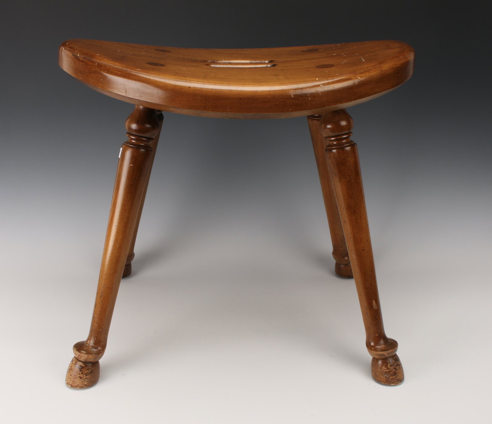 BARNARD AND SIMONDS CURVED WOODEN STOOL: Unique vintage stool by furniture maker Barnard and Simonds. The legs are pegged through to the top, the feet are carved in hoof shapes. Built in handle for easy carrying. Metal tag attached to bottom