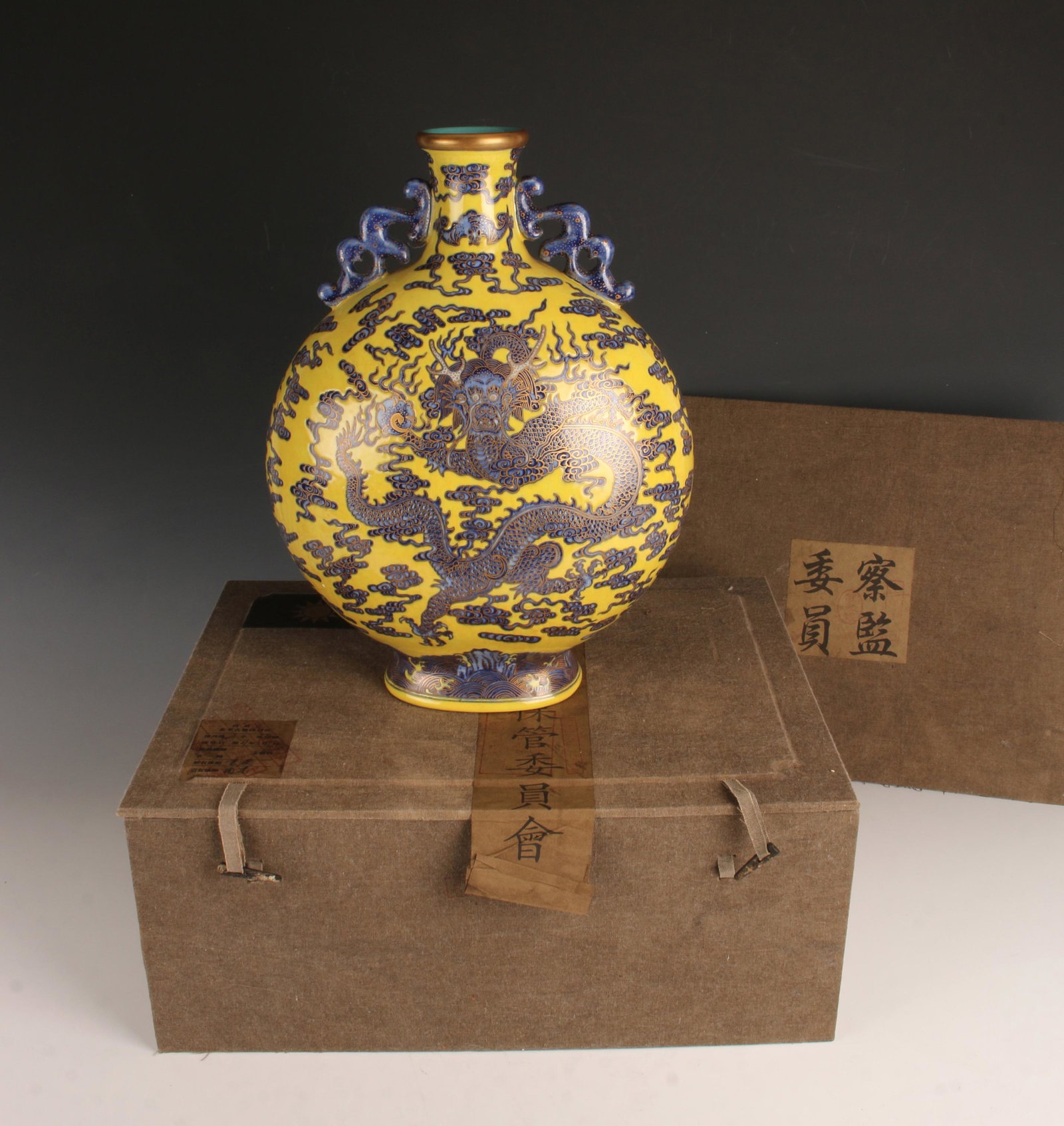 YELLOW BLUE DRAGON MOON FLASK IN PRESENTATION BOX: Pierced dragon handles, yellow body with blue dragon and gold accents. A flaming cloud filled sky fills the rest of the body. The foot has a wave pattern. Marked on the bottom. in presentation box.