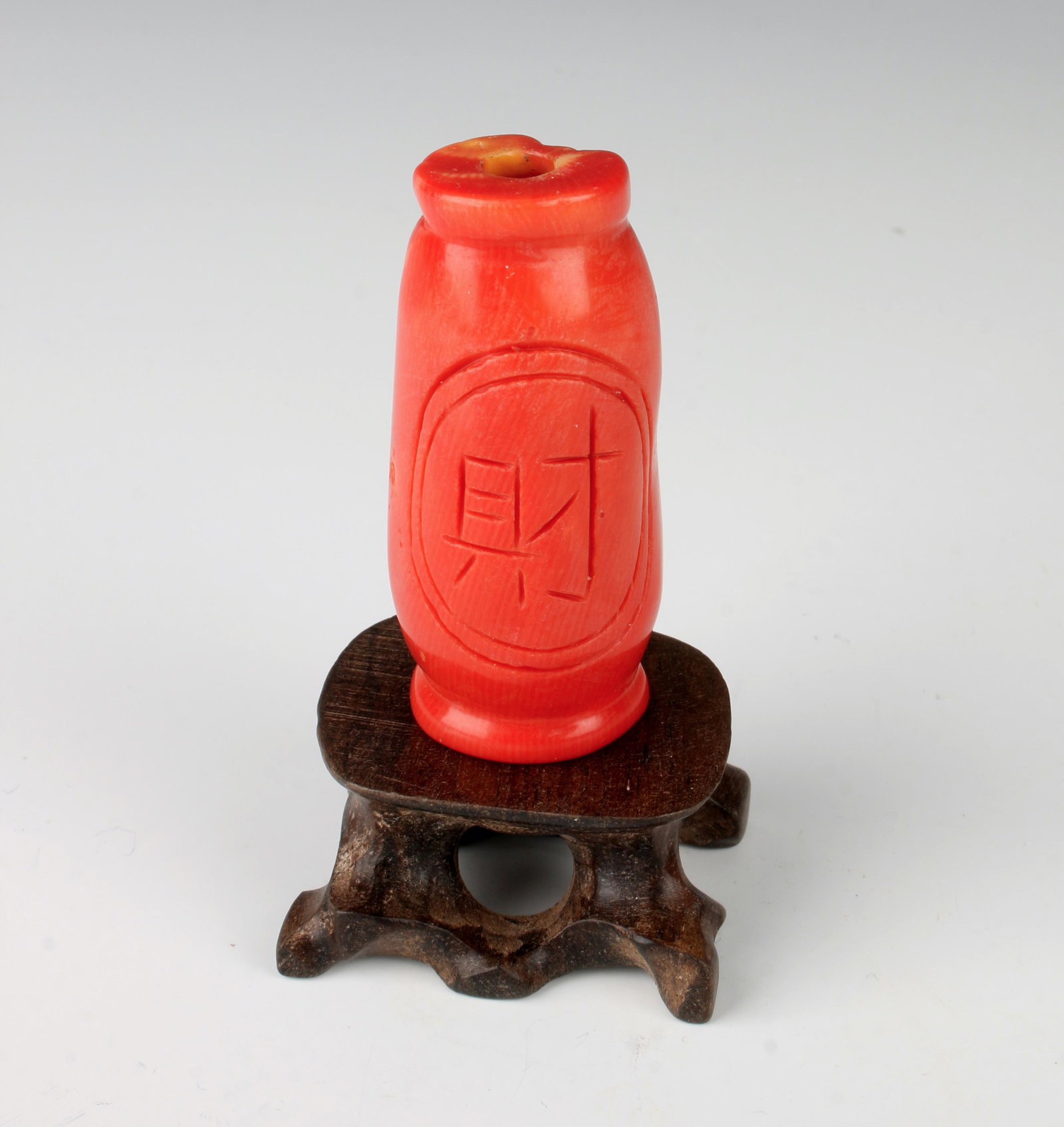 CORAL SNUFF BOTTLE ON STAND: Incised character mark on one side, natural coral formations on the other. On custom carved wood stand. 2" $100 - $200 Please contact us for high resolution images of this lot. Ship