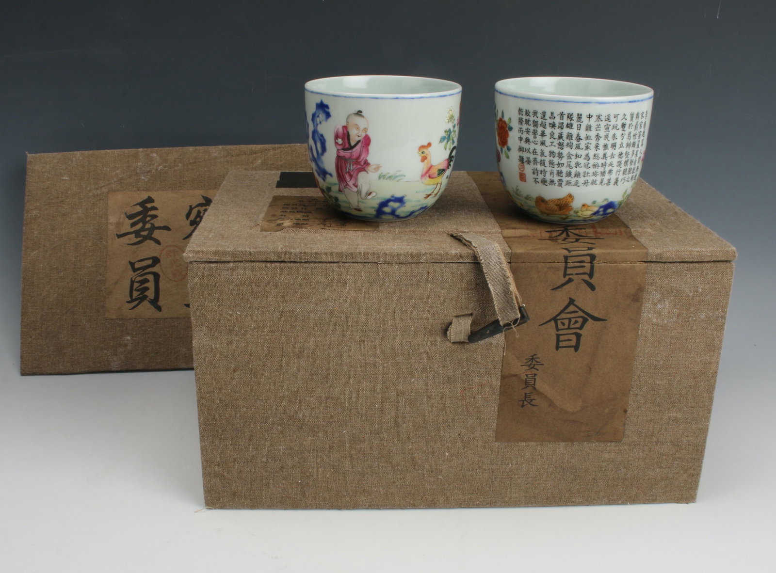 PAIR OF ROOSTER CUPS IN PRESENTATION BOX: A child is in a garden with a rooster, calligraphy with a hen and chicks on the other side. Provenance: private local collection.