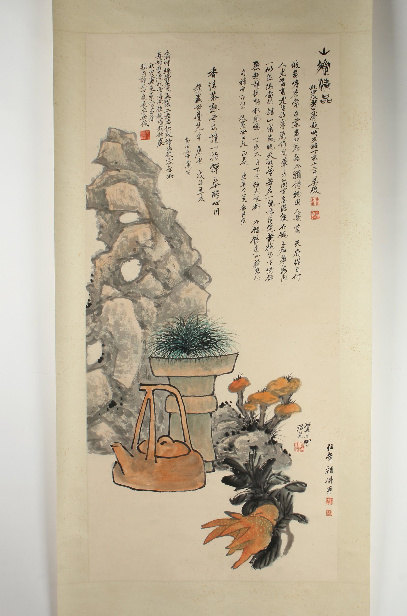 SCROLL STILL LIFE AND PLANTS: A large boulder stands behind a potted plant, tea kettle, and hand of Buddha. Calligraphy and artist mark above and lower right. Provenance: