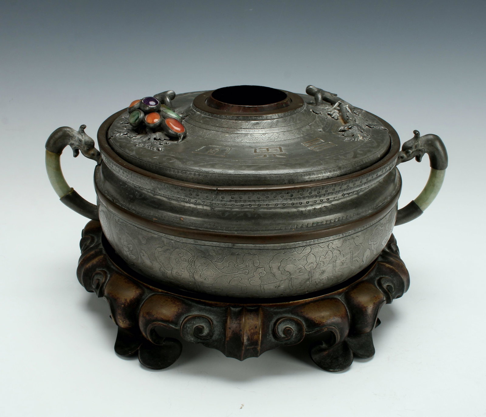 PEWTER, BRONZE AND JADE BRAZIER ON STAND: Jade and pewter dragon handles flank the central open lid to the brazier. Characters, leaves, and grapes adorn the lid. Bezel set cabochon carnelian and other hardstones form the "grapes". T