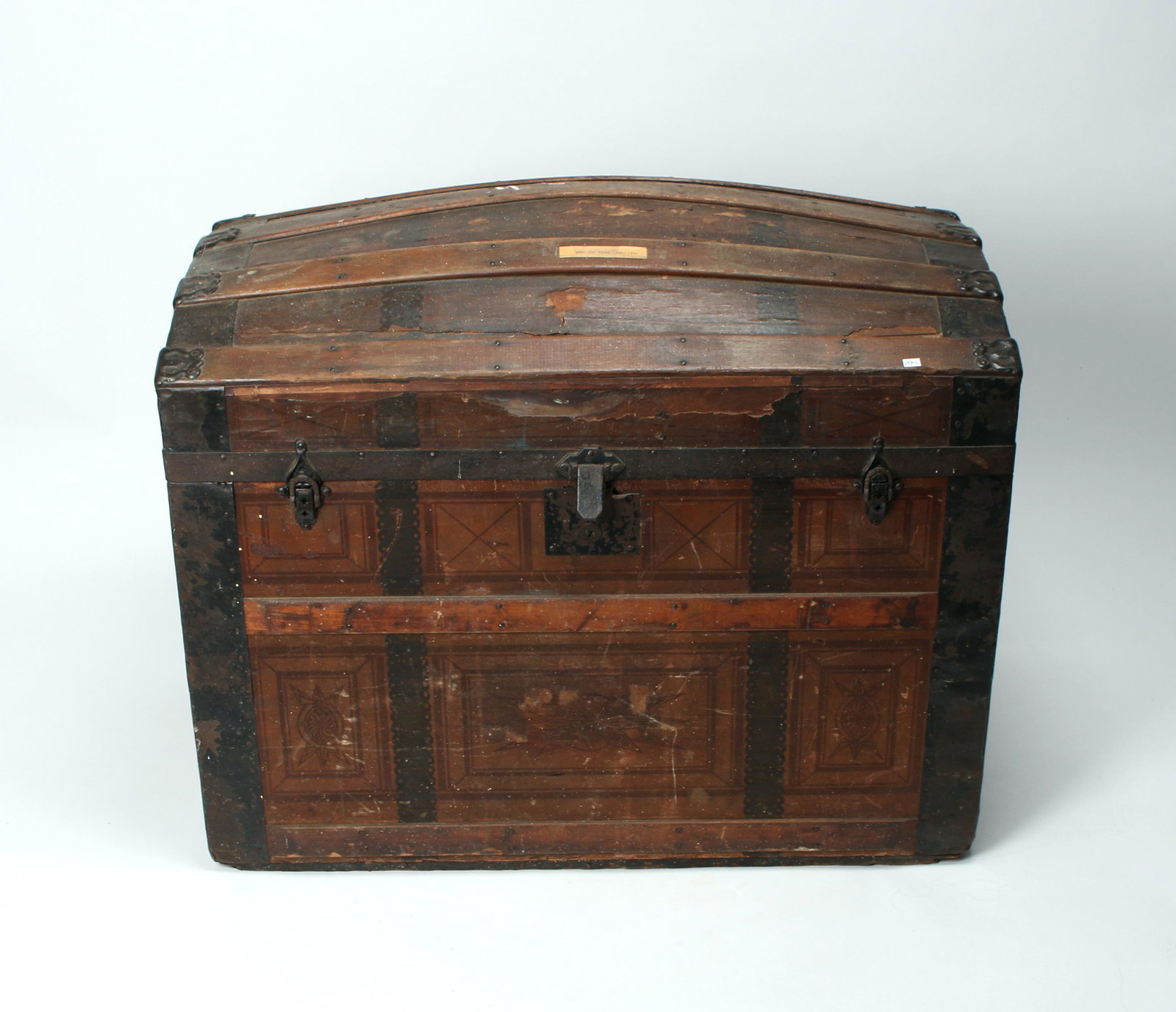 ANTIQUE WOODEN DOME TOP TRUNK C. 1850 - 1900: Unusual designs in brown and black all over. Metal hinges and strapping. The back has an age crack along bottom slat. Lithography on interior lid of an Arts and Crafts style design. 34" X 21"