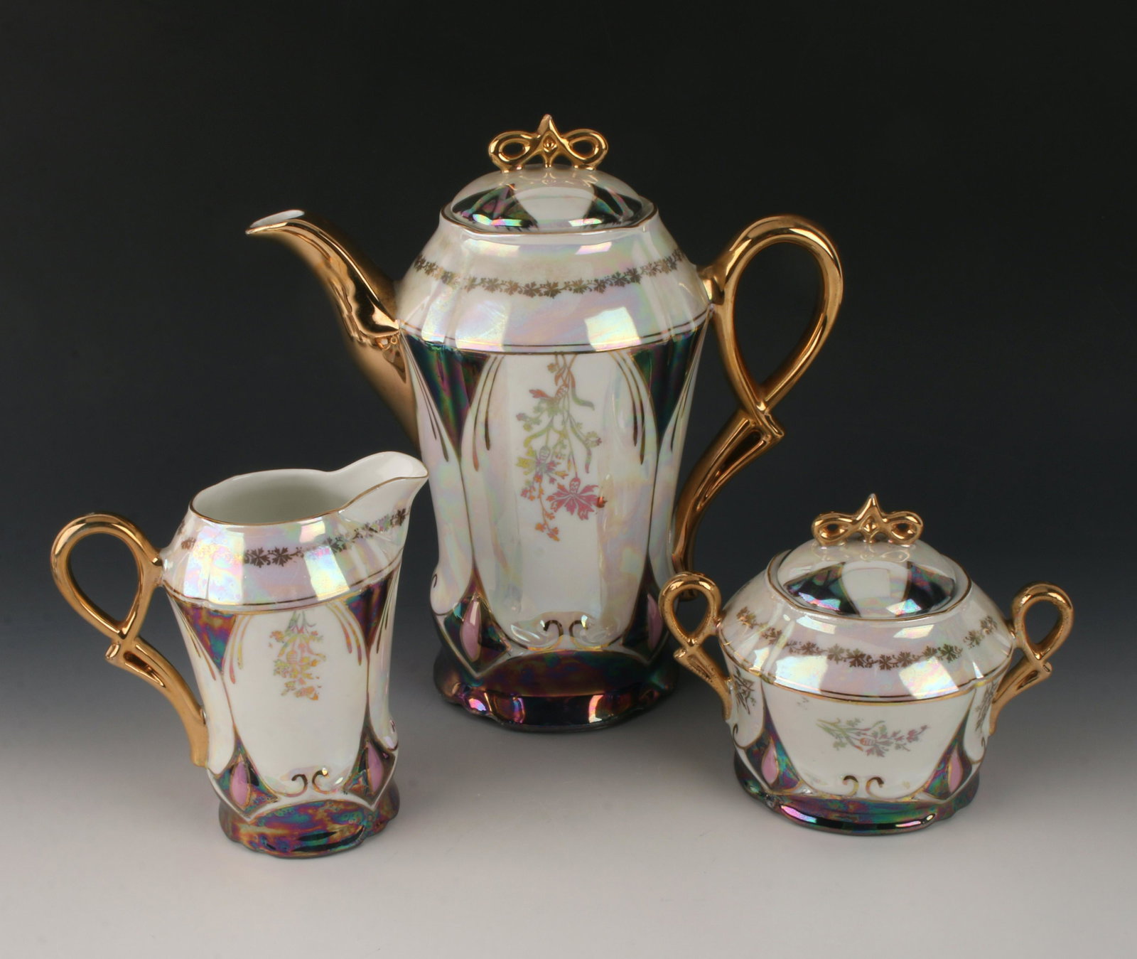 ART NOUVEAU LUSTERWARE COFFEE SET: Marked RW made in Germany within a circle. Art Nouveau style with gold handles and spout. Includes coffee pot, sugar and creamer, and four demitasse cups and saucers. Iridescent and pearlized lusterwa