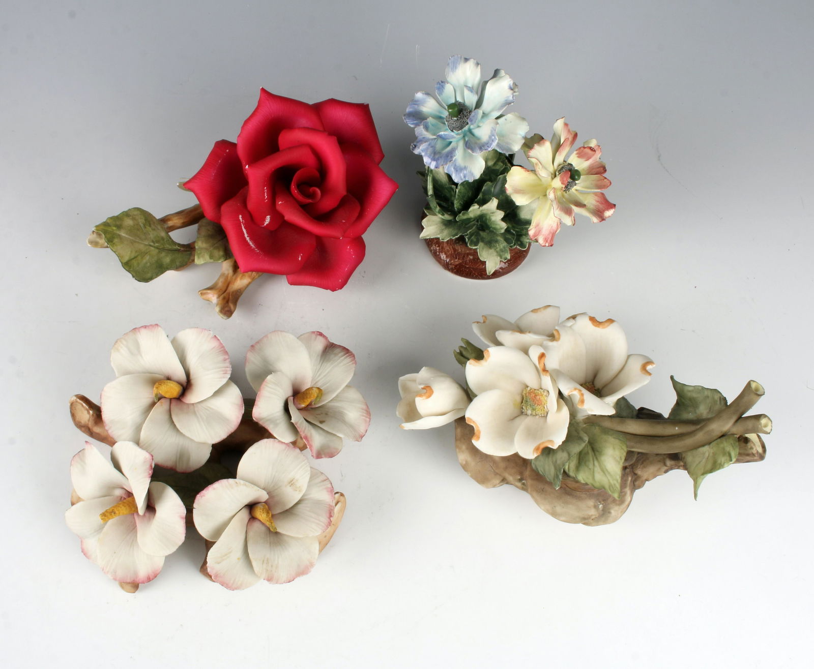 4 CAPODIMONTE PORCELAIN FLOWER GROUPINGS: Life sized flowers on realistic branches delicately made and brightly colored. A charming addition to any table top arrangement. 7" X 2 1/2" $40 - $80 Please contact us for high resol