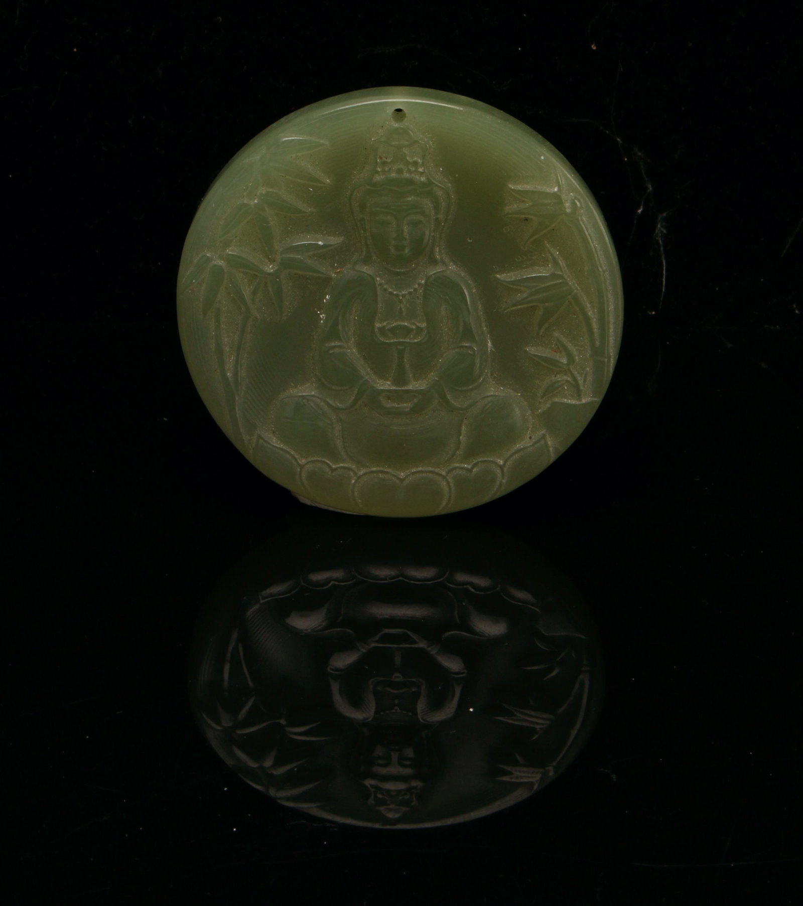 JADE BUDDHA CARVED PENDANT: Carved Buddha sits in a bamboo garden. Pierced at the top for hanging. Provenance: private collection. 2"