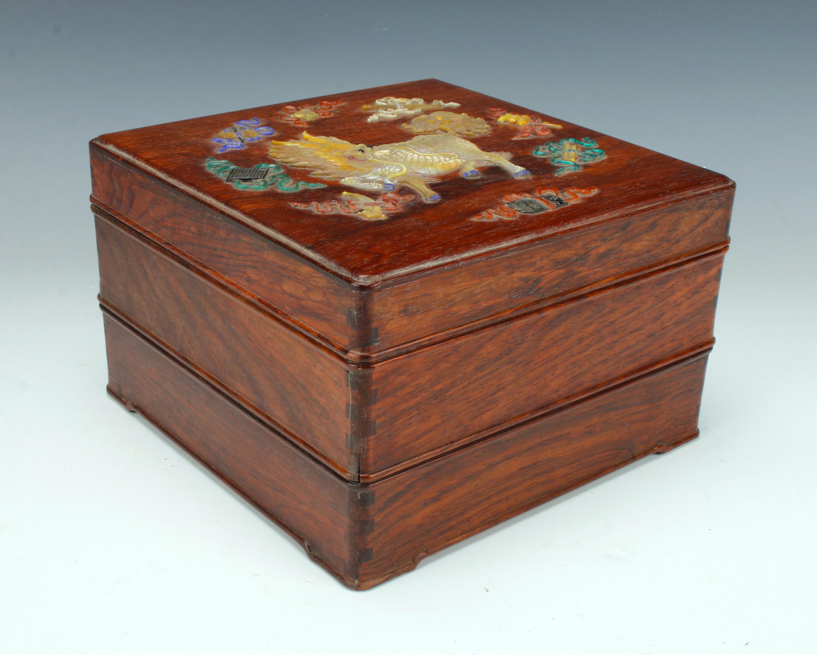 THREE TIERED APPLIED HARD STONE HUANGHUALI BOX: A kirin is on the lid surrounded by scholar's items. Box in three tiers with four raised feet on the bottom. Provenance: private collection.