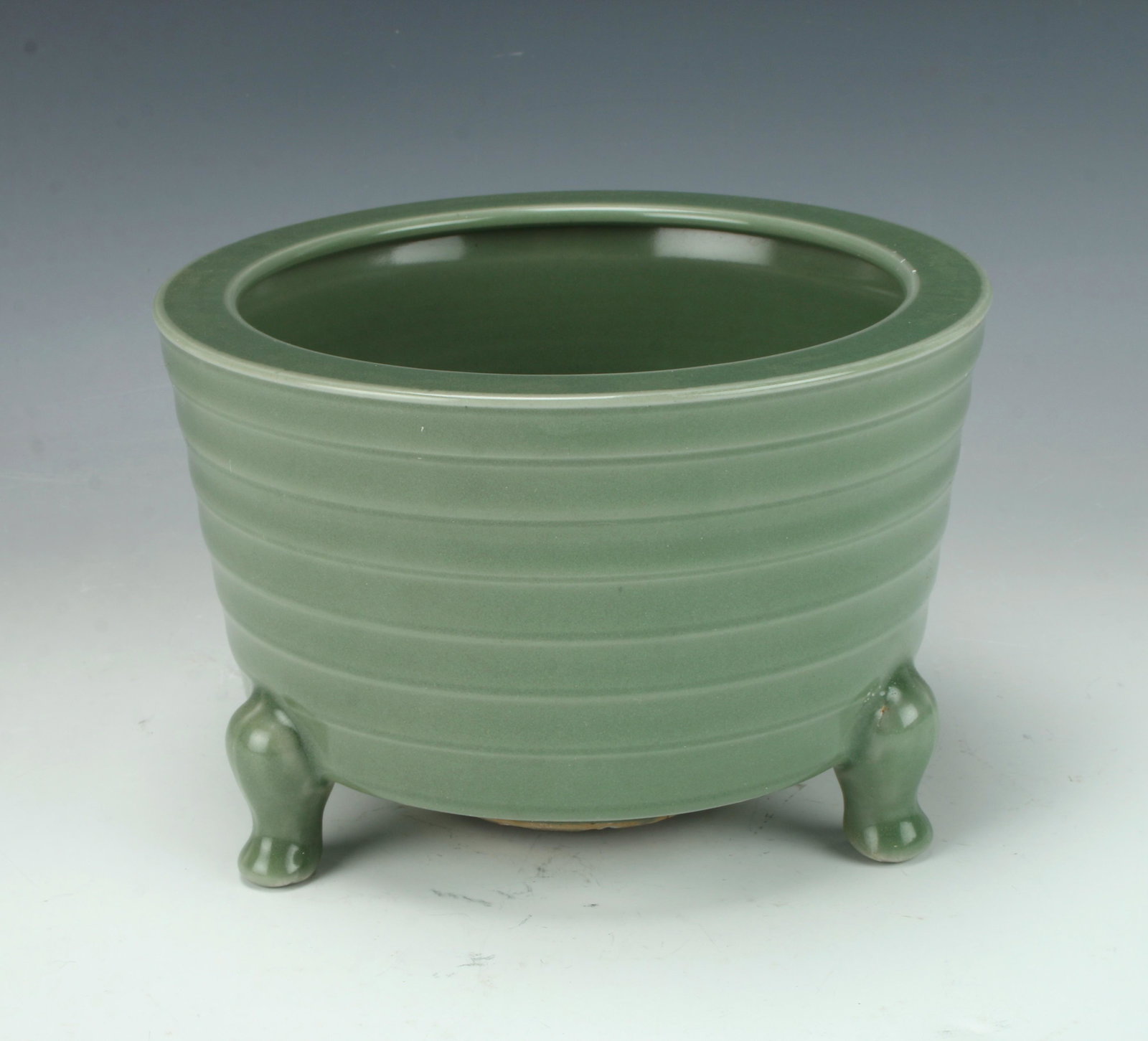 ROUND PORCELAIN CELADON TRIPOD POT: Ridged pattern on the body on tripod feet. Provenance: private collection. 6 3/4" X 4 1/2" $6