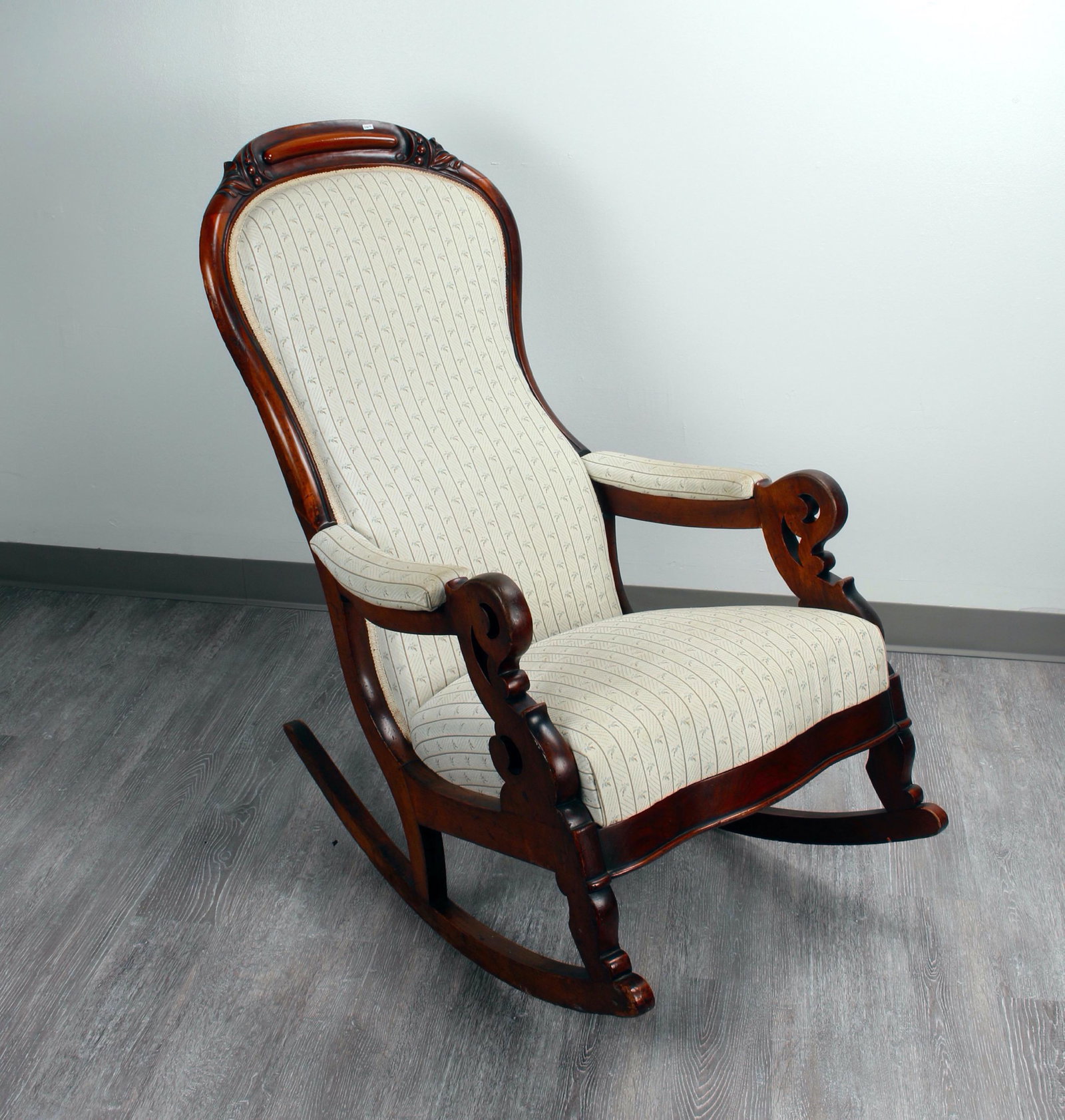 QUEEN ANNE SCROLL ARM ROCKER: Shaped back. Upholstered back, seat and arms. Carved top in stylized leaves. Solidly constructed. 24 1/2" X 41" $100 - $200 Please contact us for high resolution images of this lot. <