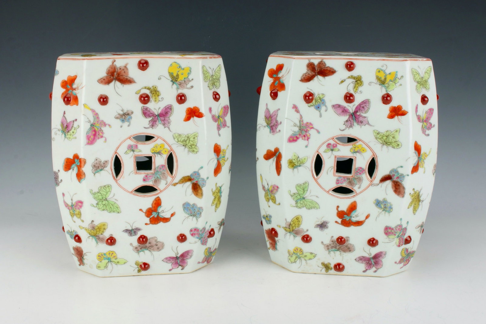 PAIR OF SMALL BUTTERFLY GARDEN SEATS: Many multicolored butterflies flutter around the body of the stools. The top and sides are pierced with a lucky coin design. Great pieces for decorating your outdoor space this summer! 7 3/4" X 10 3/4