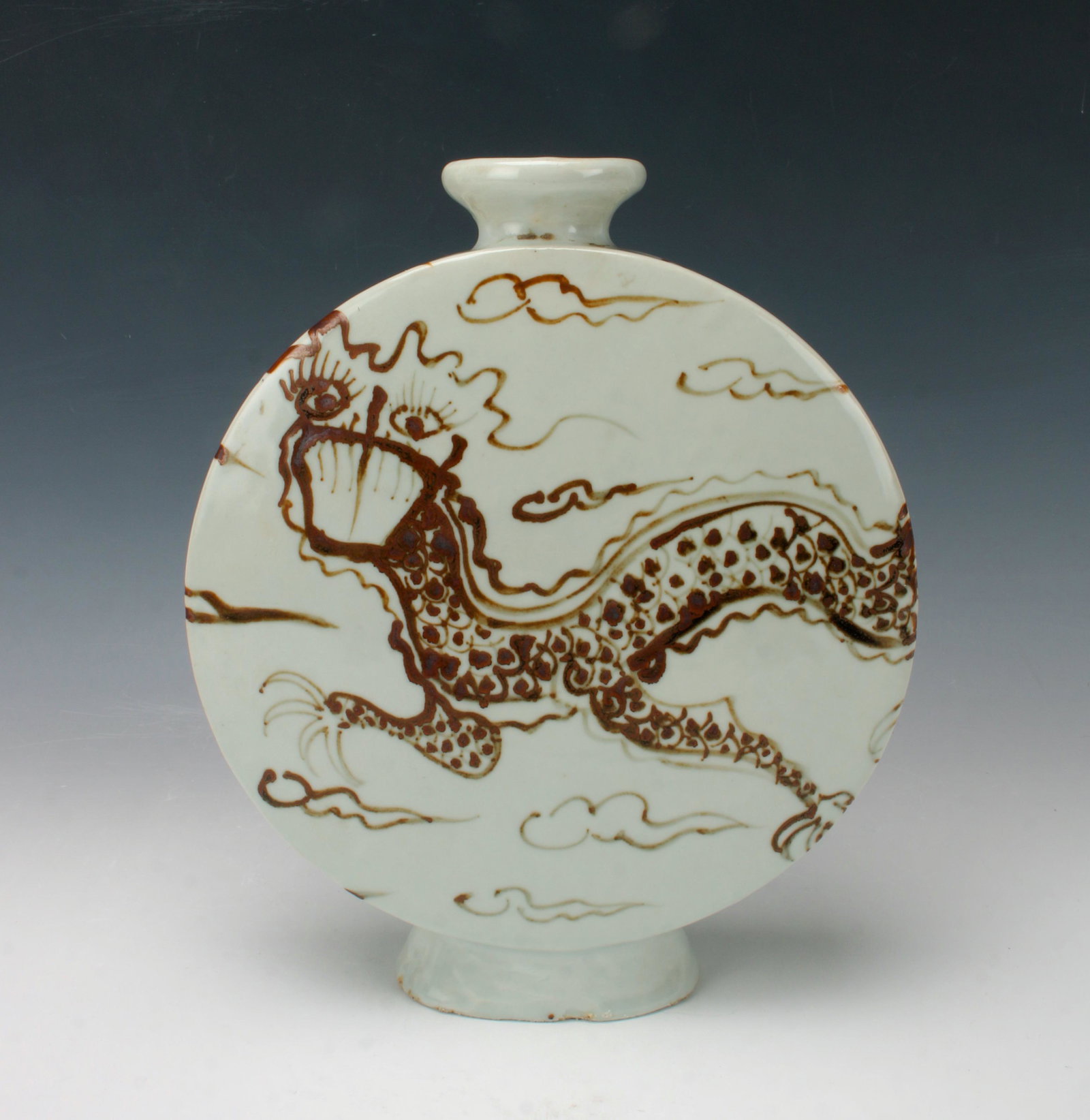 KOREAN DRAGON MOON FLASK: A dragon spans the two large flat sides and one thin side while flying among clouds. Provenance: private collection.