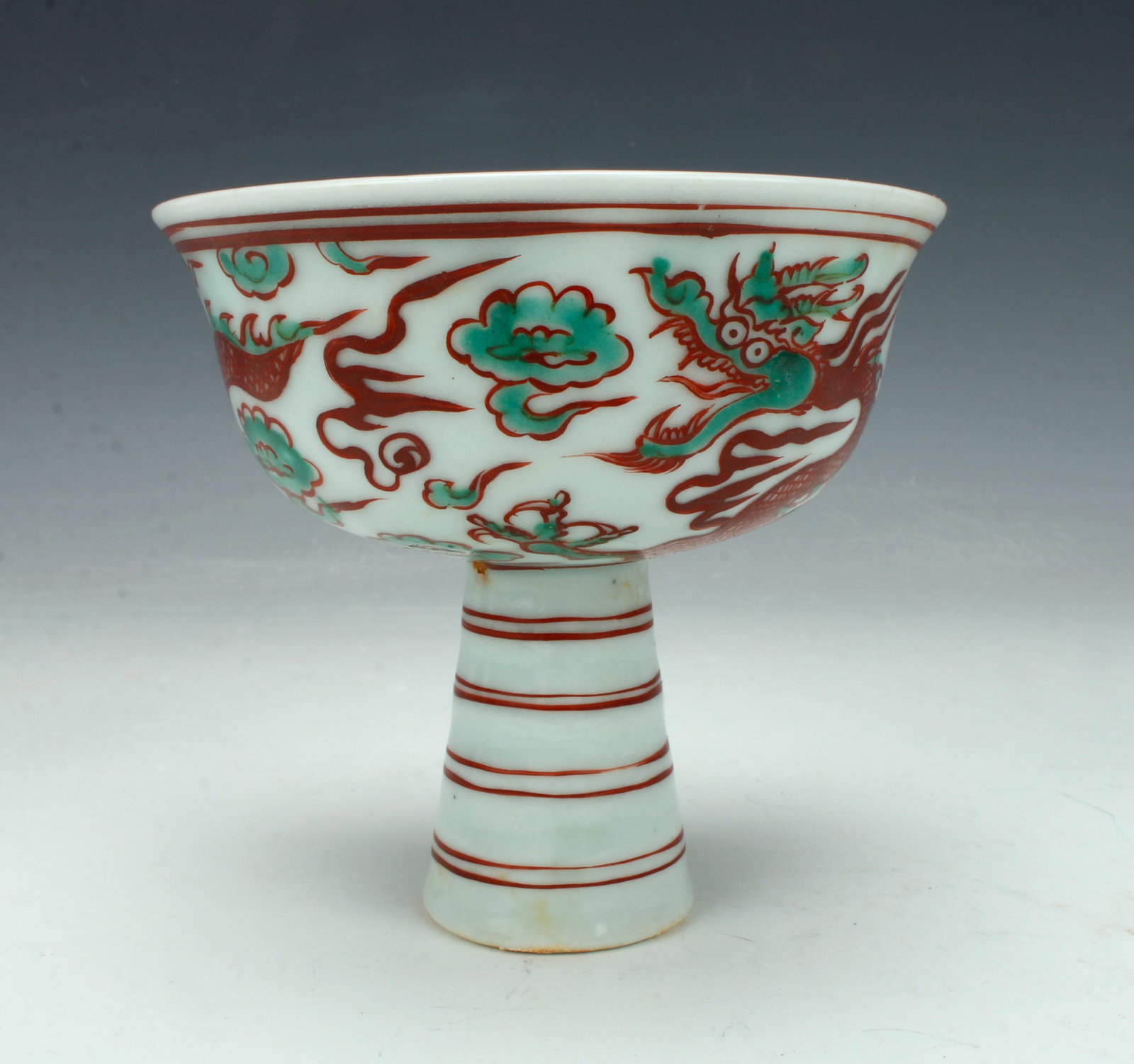 CHINESE HIGH HEELED DRAGON CUP: Large dragon on the outside with flaming clouds and flaming pearls. The interior has a lotus blossom surrounded by leaves. The foot is tall and striped. Provenanc